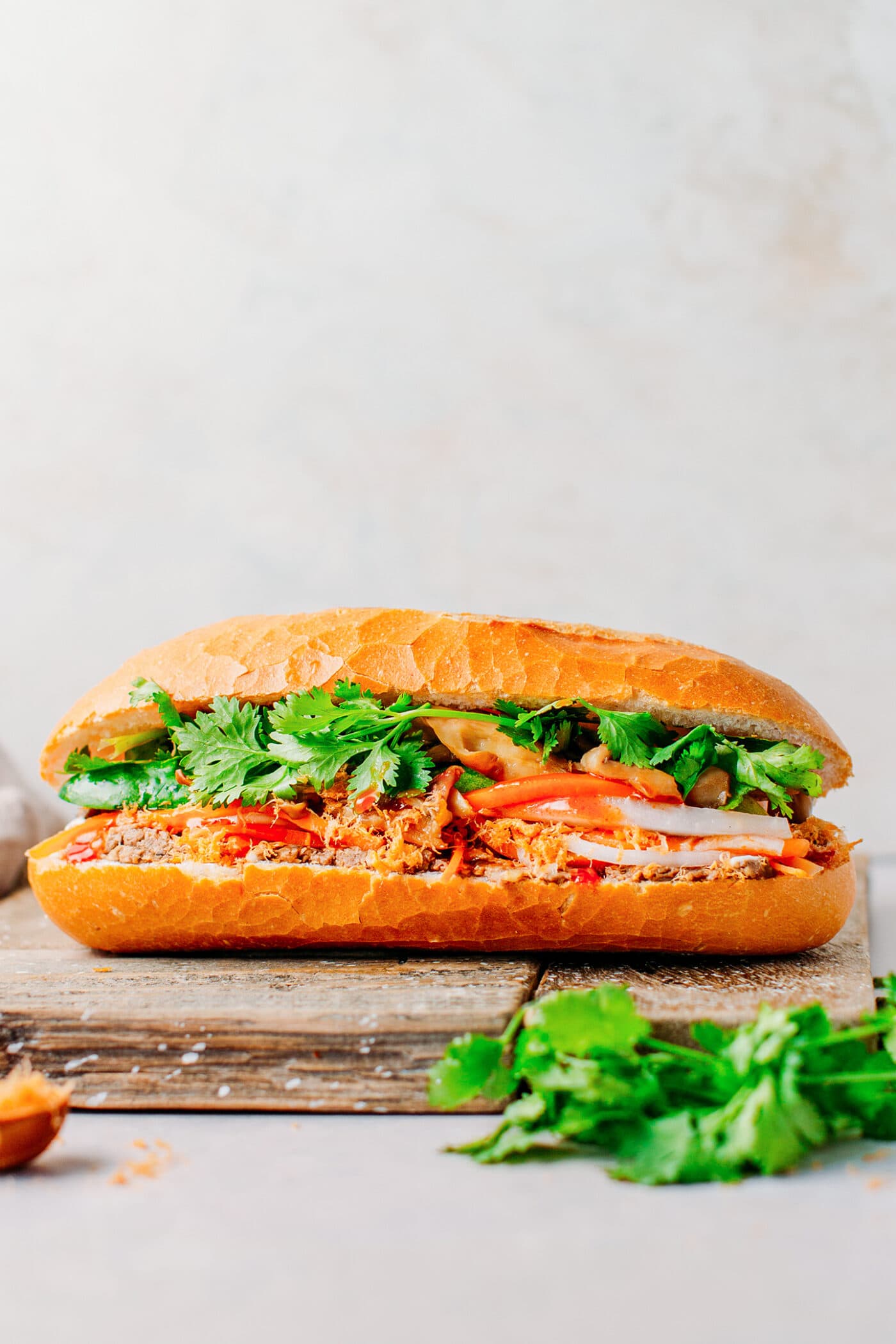 Vegan banh mi sandwich filled with mushrooms, tofu, paté, pickles, and cilantro.