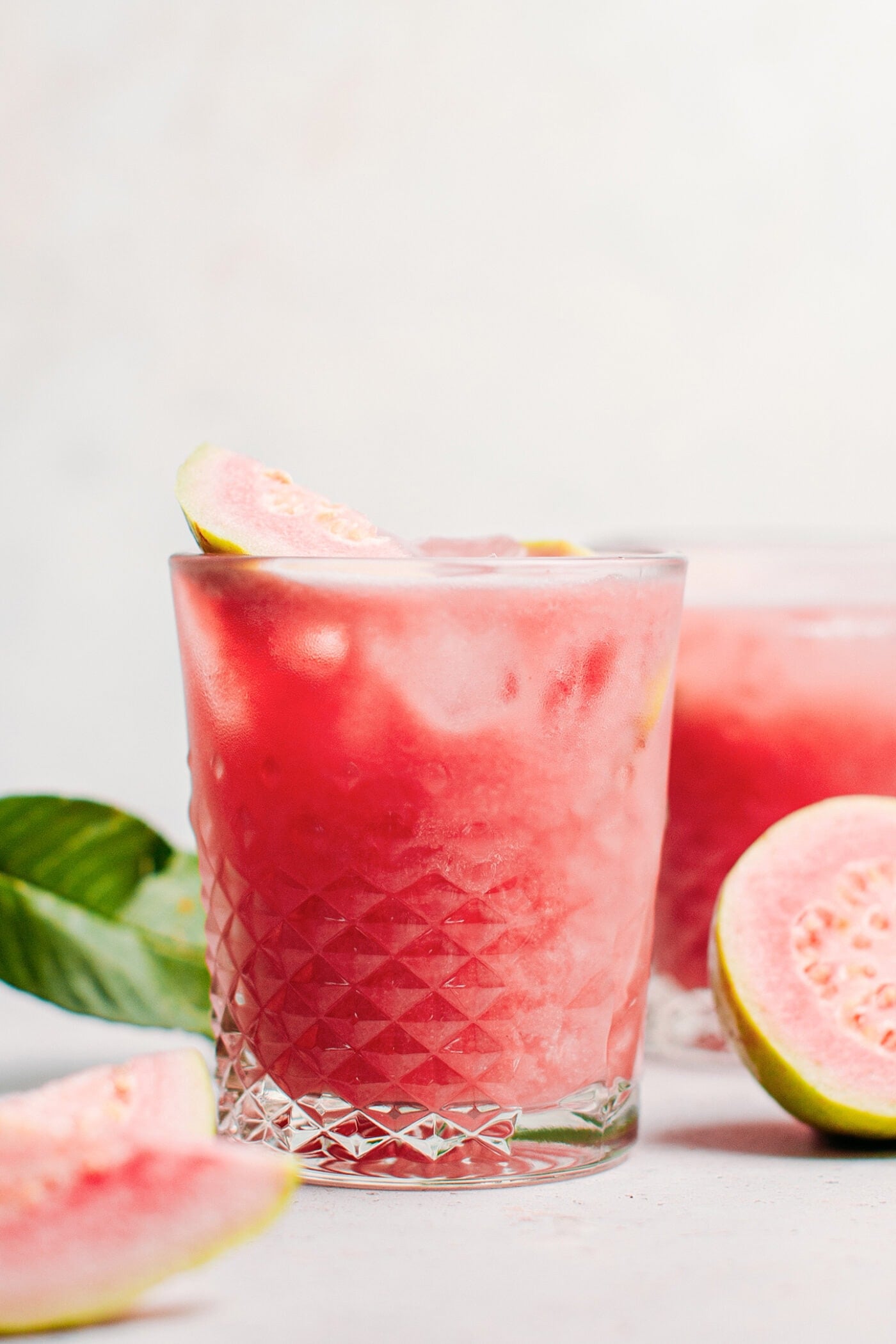 Guava iced tea in a glass with fresh guava slices.