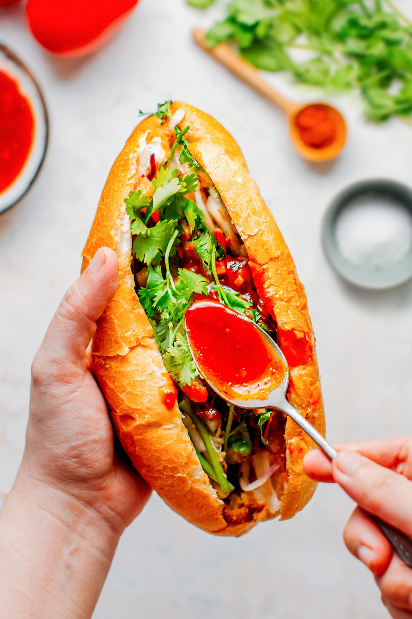 Pouring tomato sauce into a Bánh Mì sandwich.