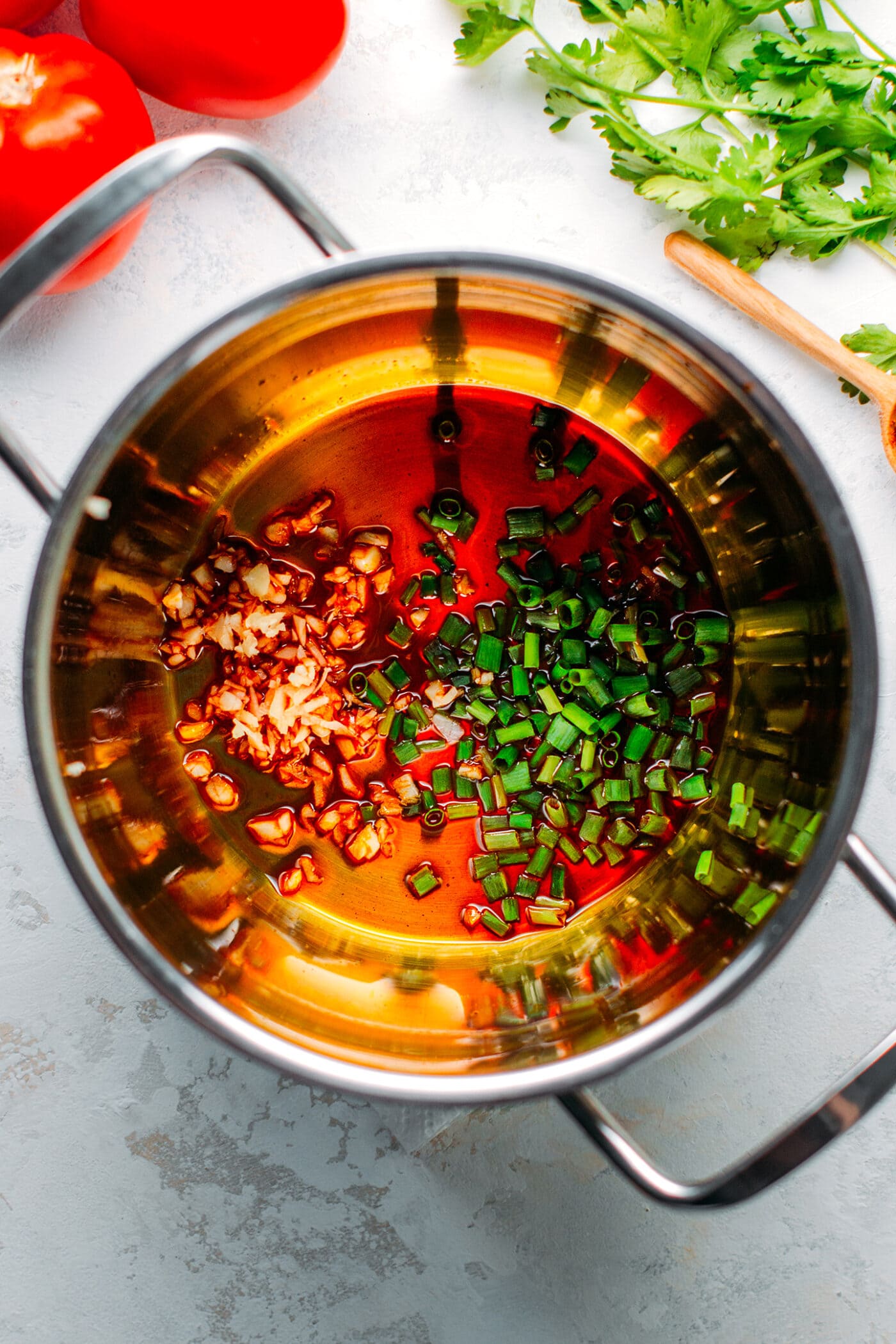 Sautéed garlic, shallots, and green onions in a saucepan.