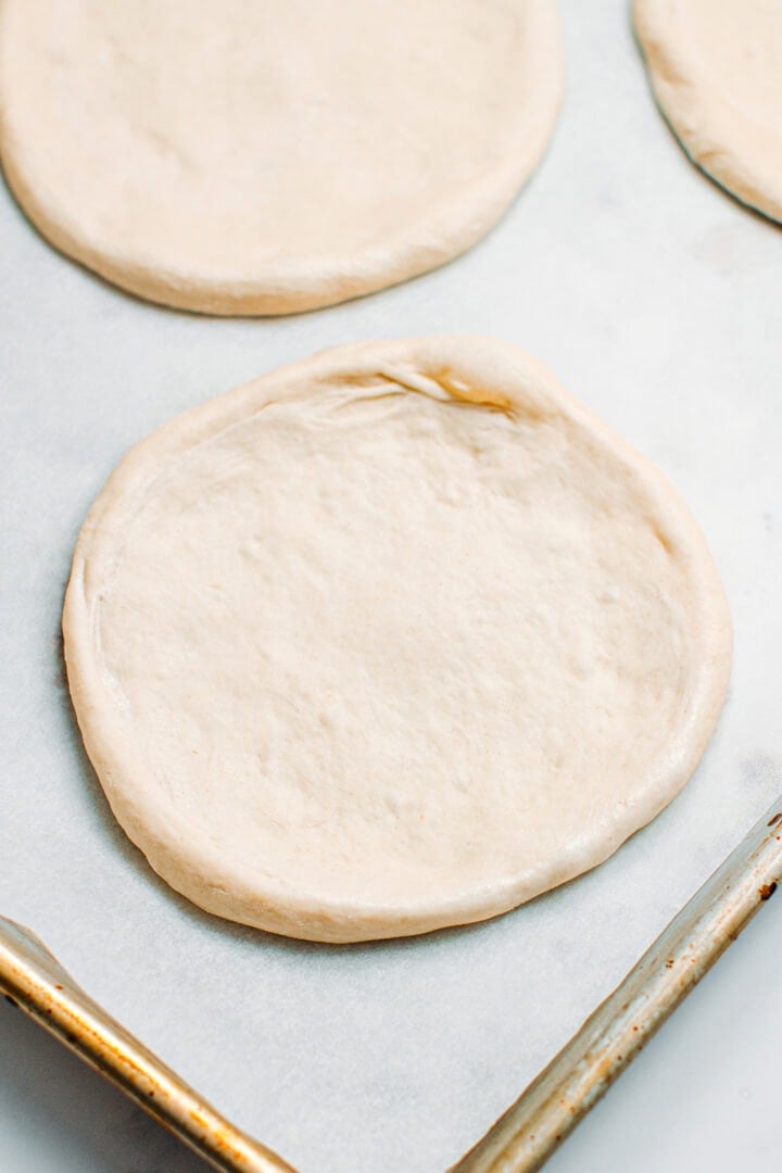 Stretched pizza dough on a baking sheet.