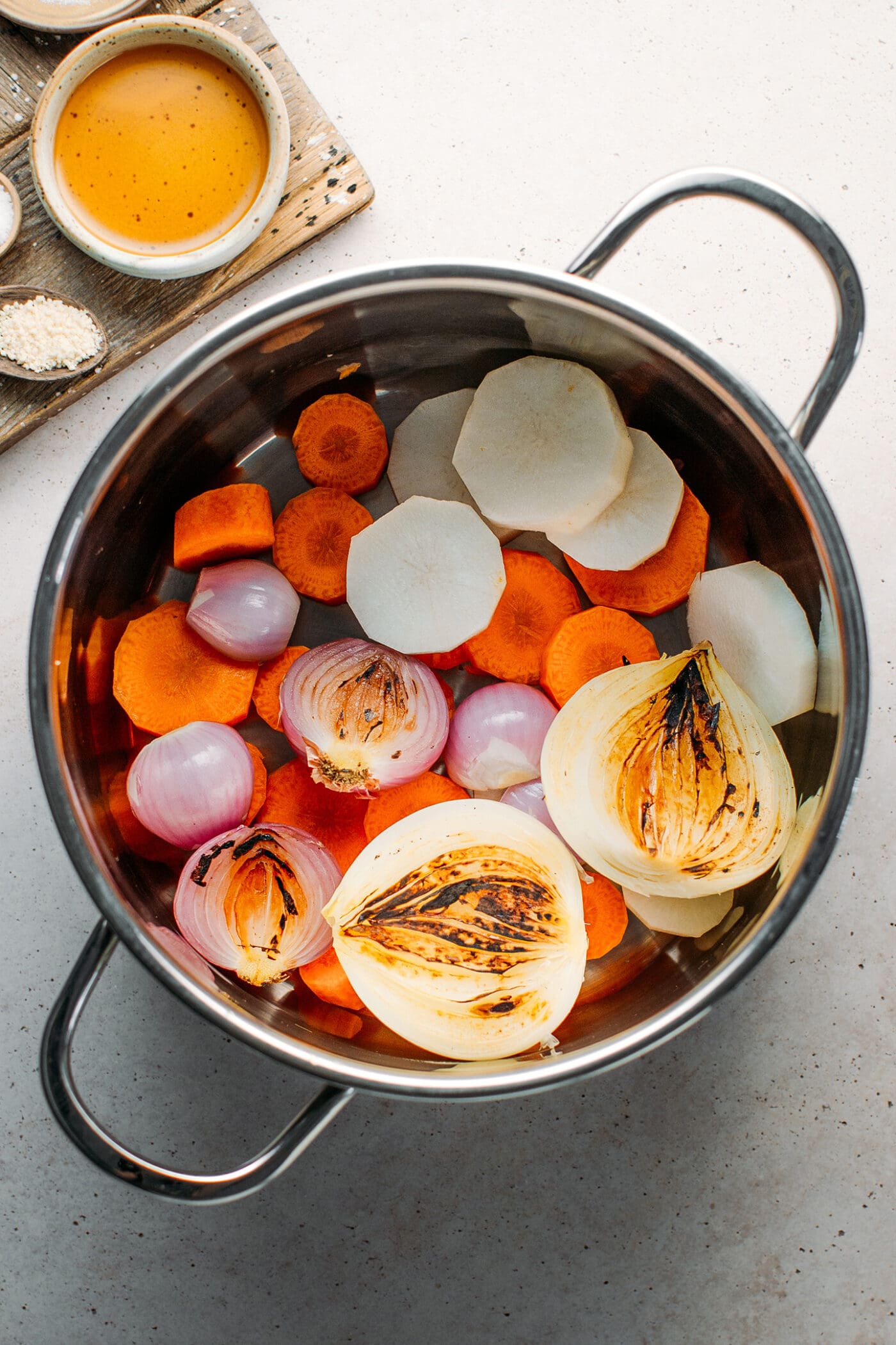 Carrots, radish, onions, and shallots in a pot.