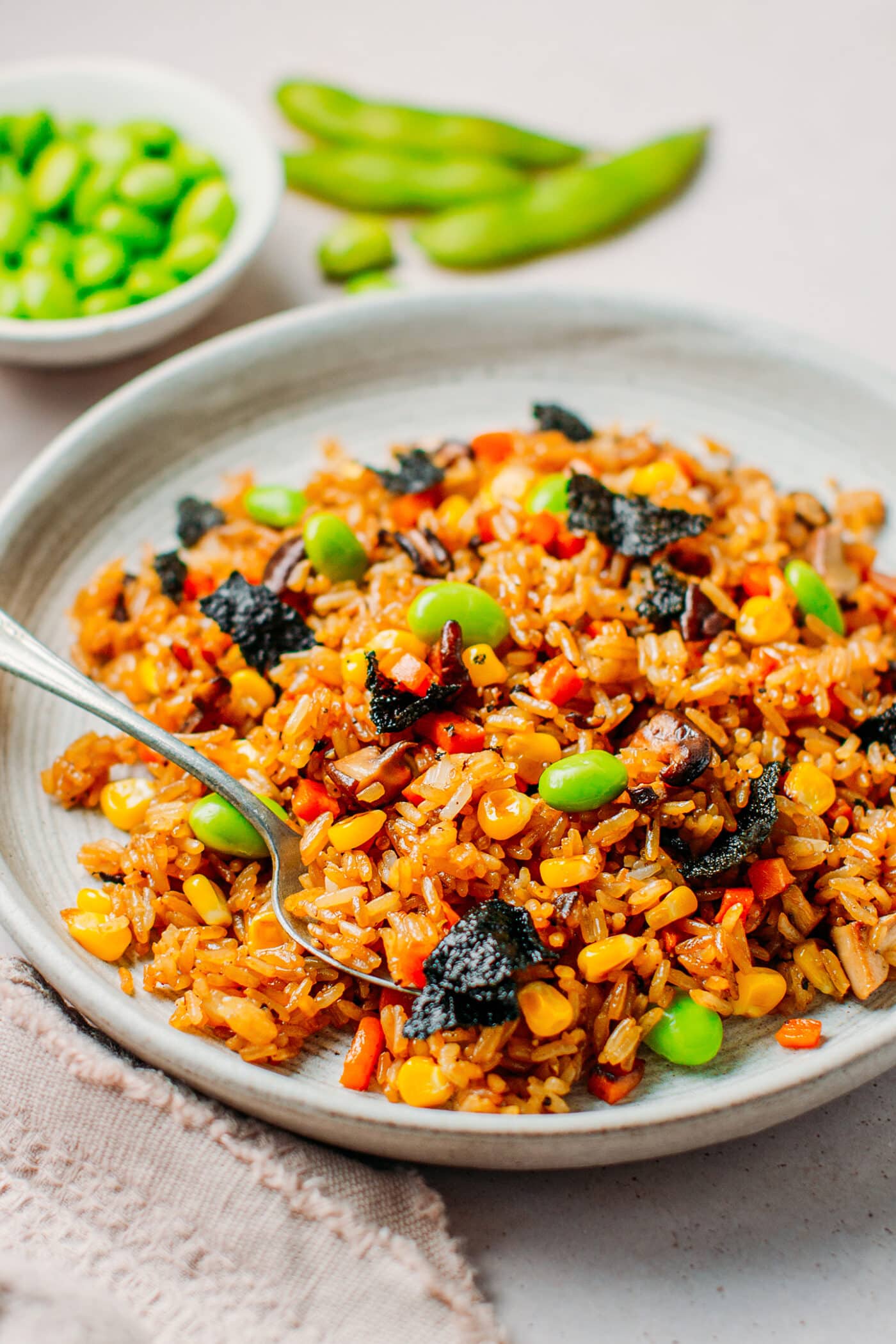Close up of vegetarian fried rice with corn, mushrooms, edamame, and nori seaweed.