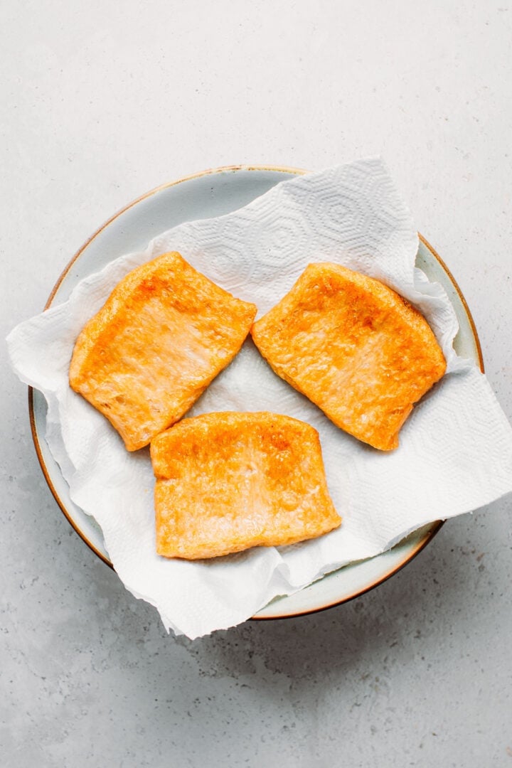 Fried TVP slices on a plate lined with kitchen paper towels.