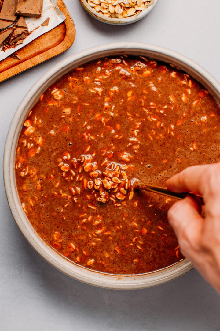 Stirring rolled oats with cacao powder, hazelnut butter and almond milk.