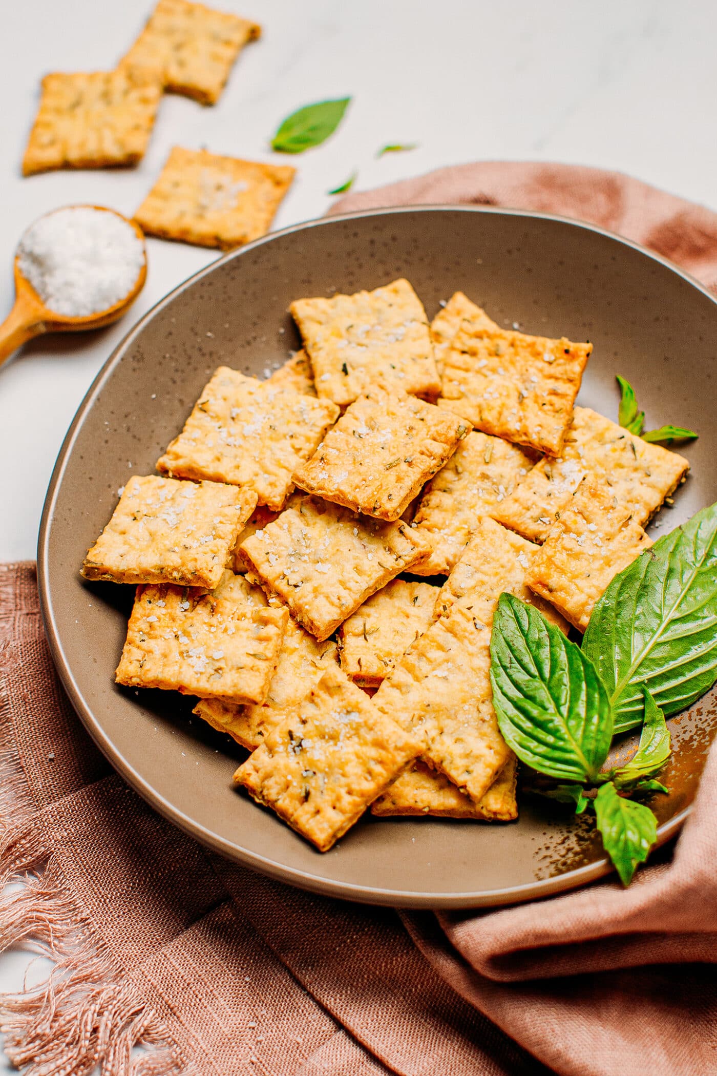 Herb crackers on a plate with sea salt and fresh basil.