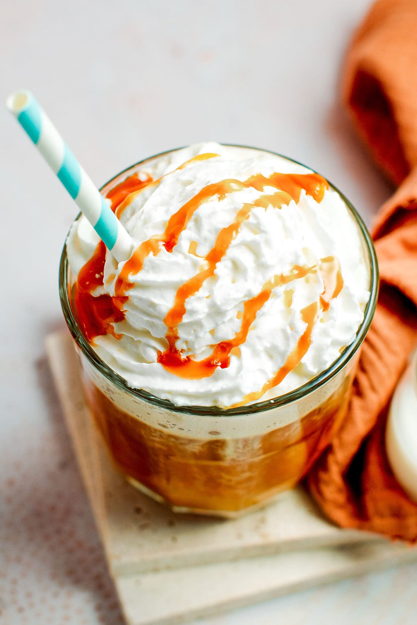 Glass of caramel latte topped with whipped cream.