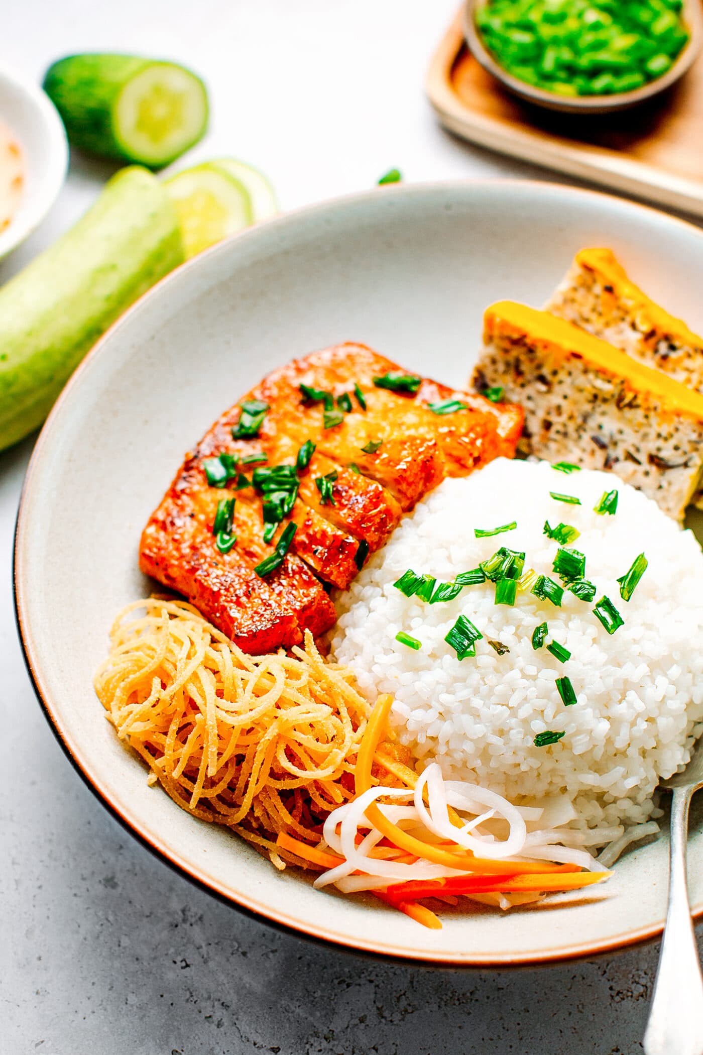 Close up of Vietnamese broken rice with tofu meatloaf, vegan ribs, cucumber, and pickles.