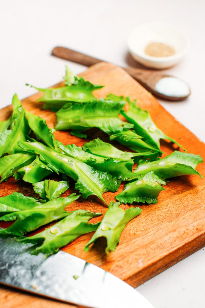 Sliced winged beans on a cutting board.