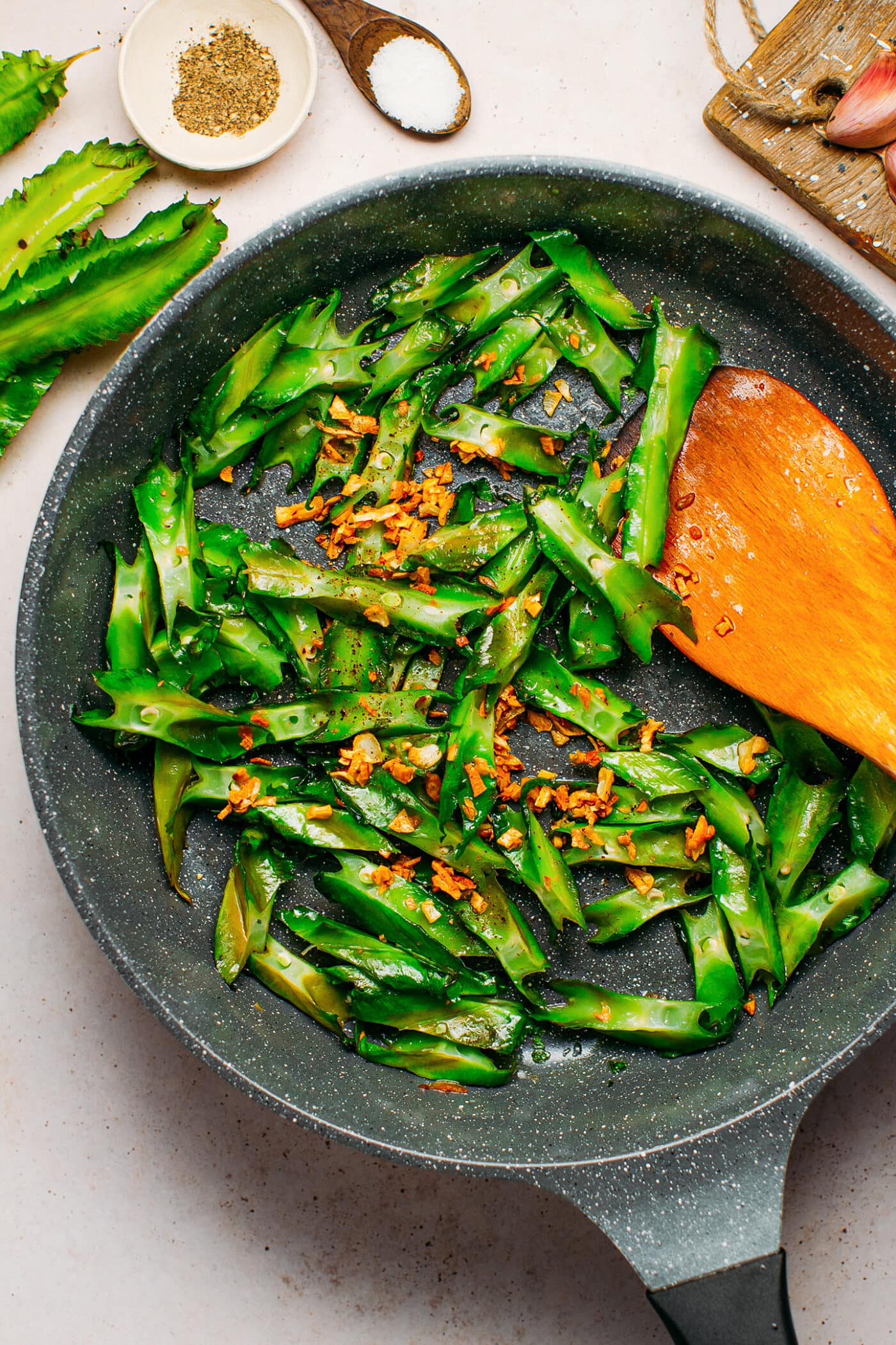 Sautéed winged beans with garlic in a skillet.