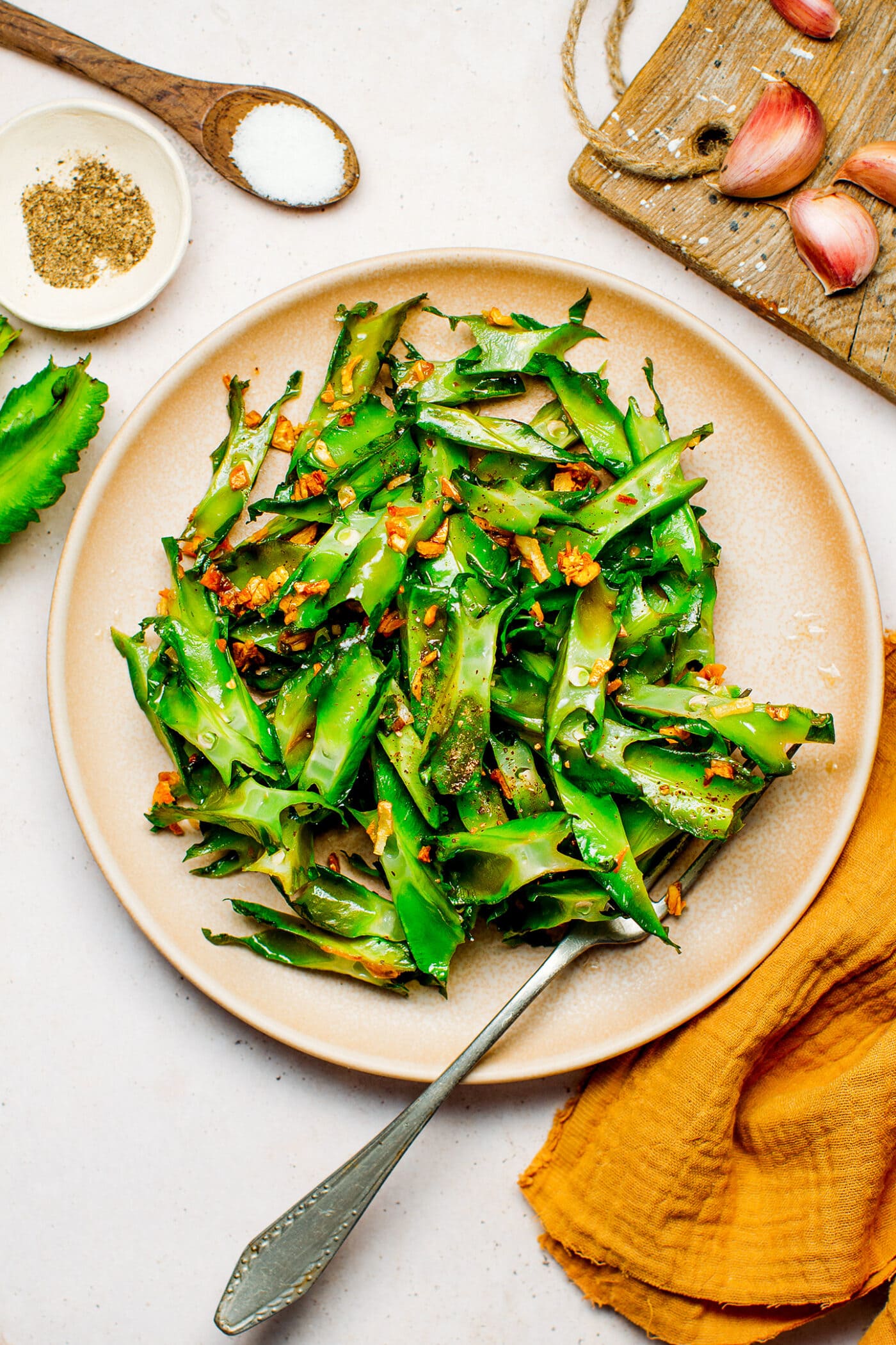 Sautéed winged beans with crispy garlic on a plate.