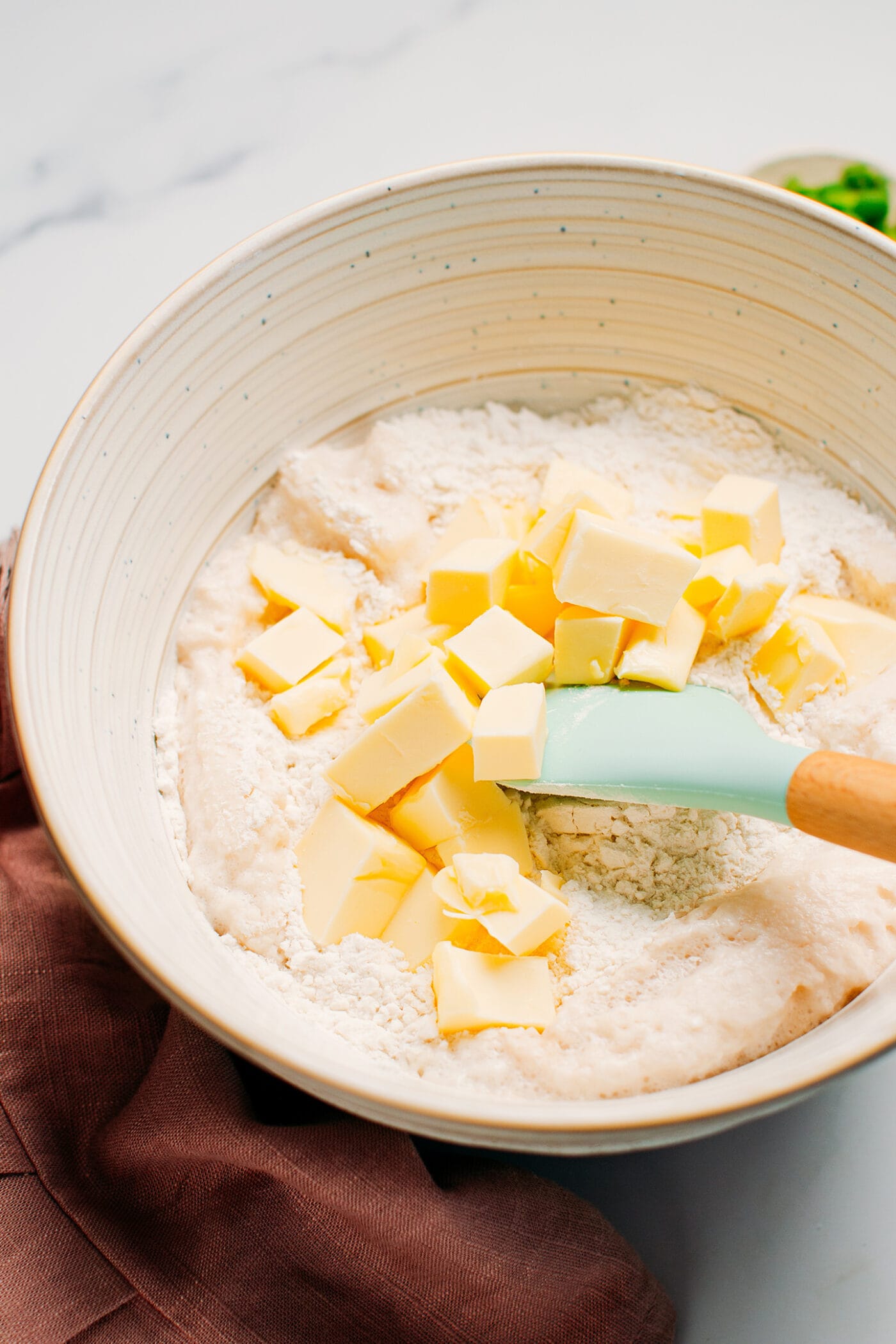 Mixing butter with flour and yeast in a bowl.
