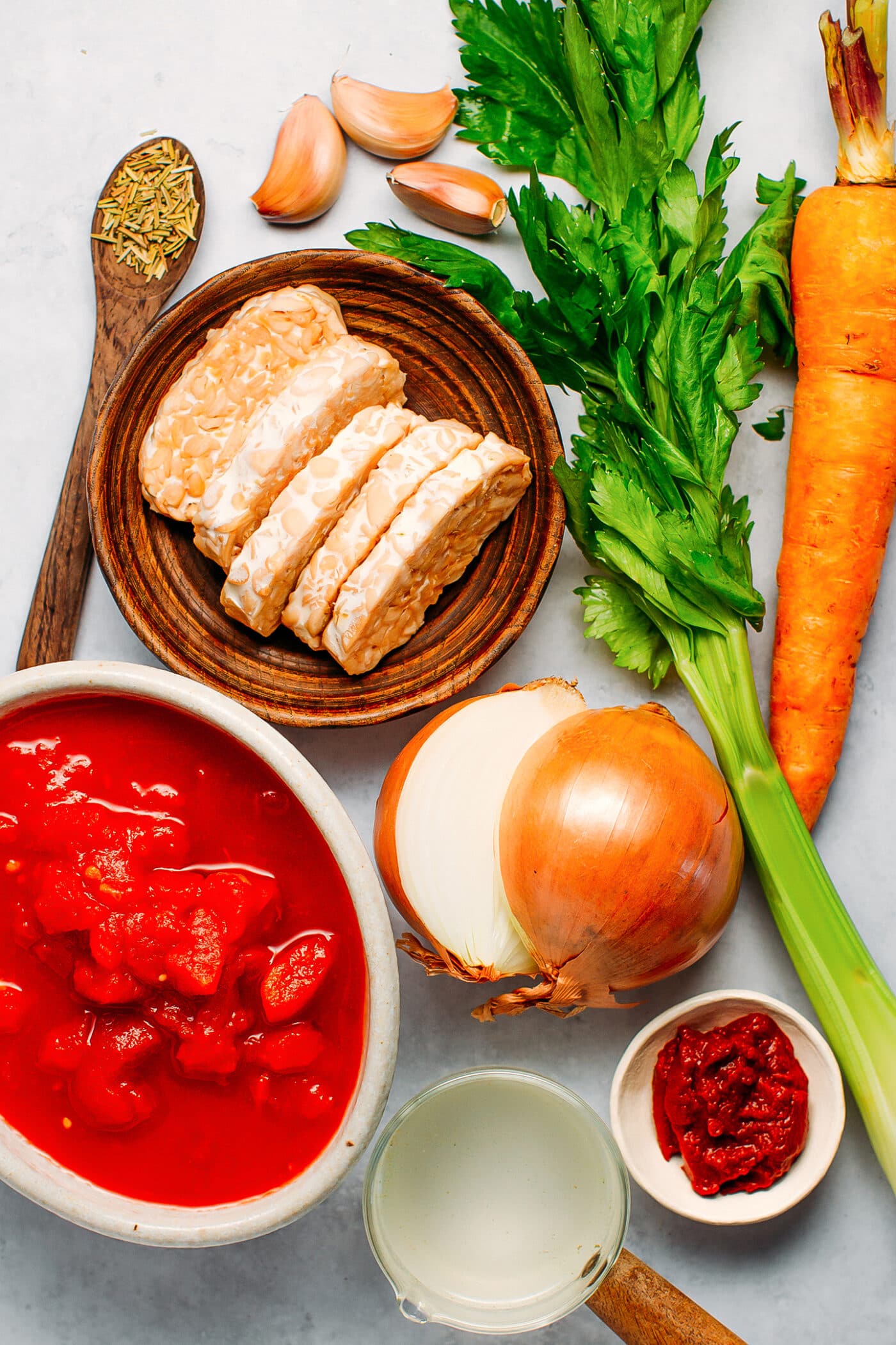Ingredients like tempeh, carrots, celery, diced tomatoes, onions, and garlic.