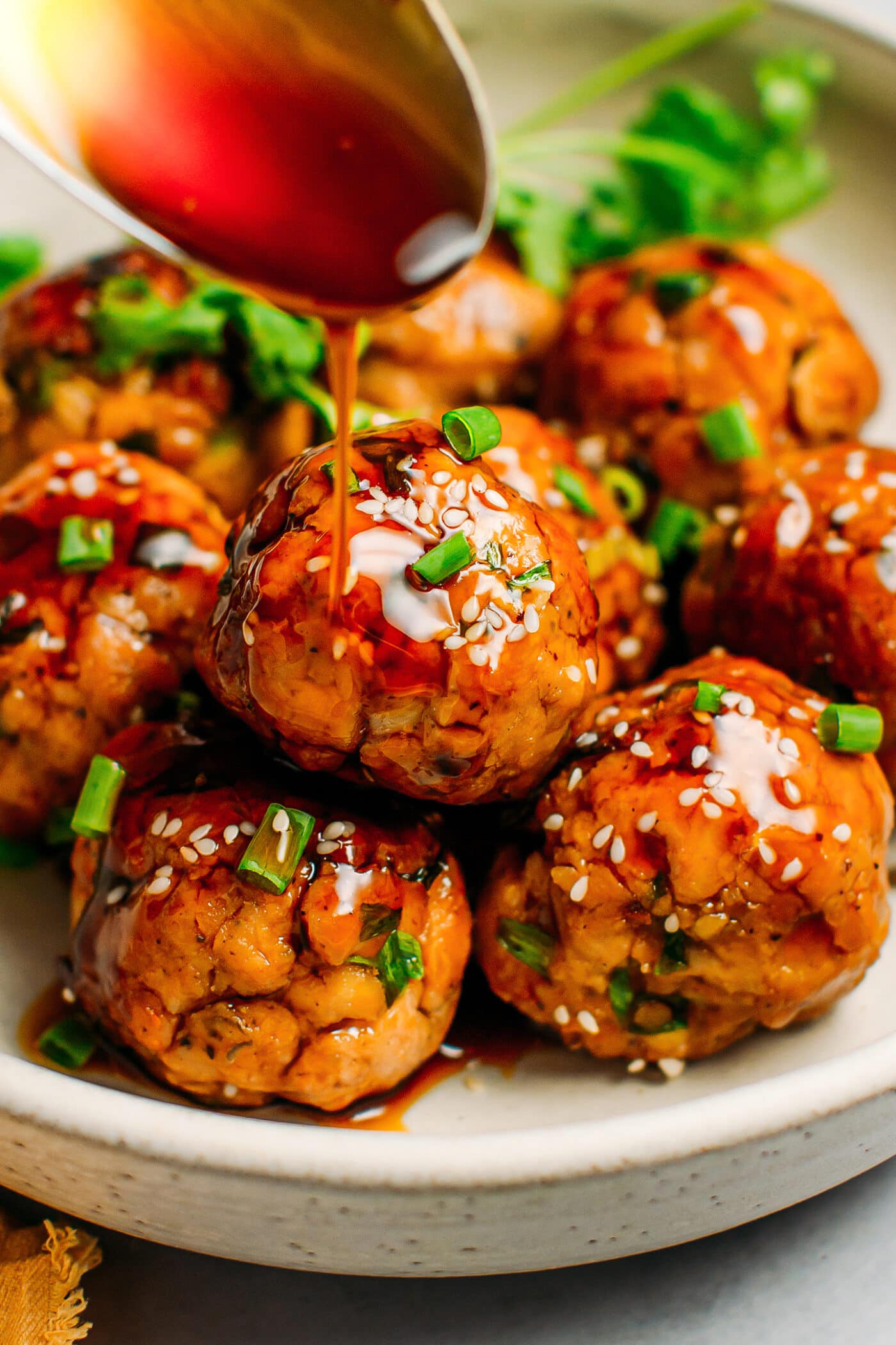 Teriyaki tempeh meatballs topped with sesame seeds and green onions.