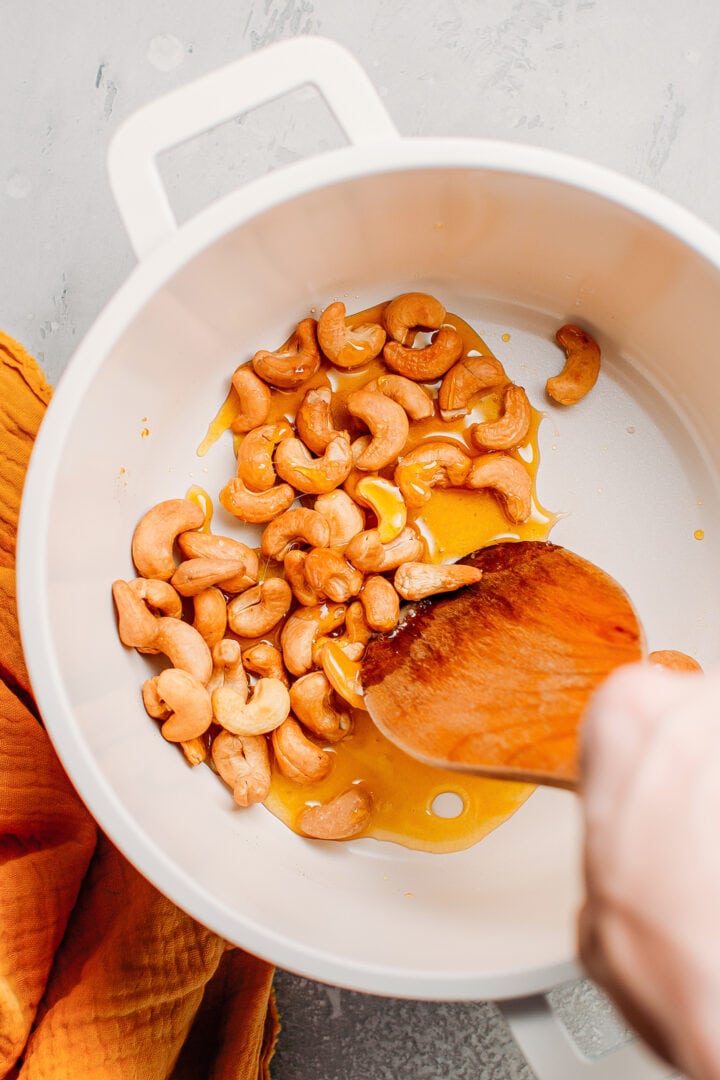 Coating roasted cashews with caramel.