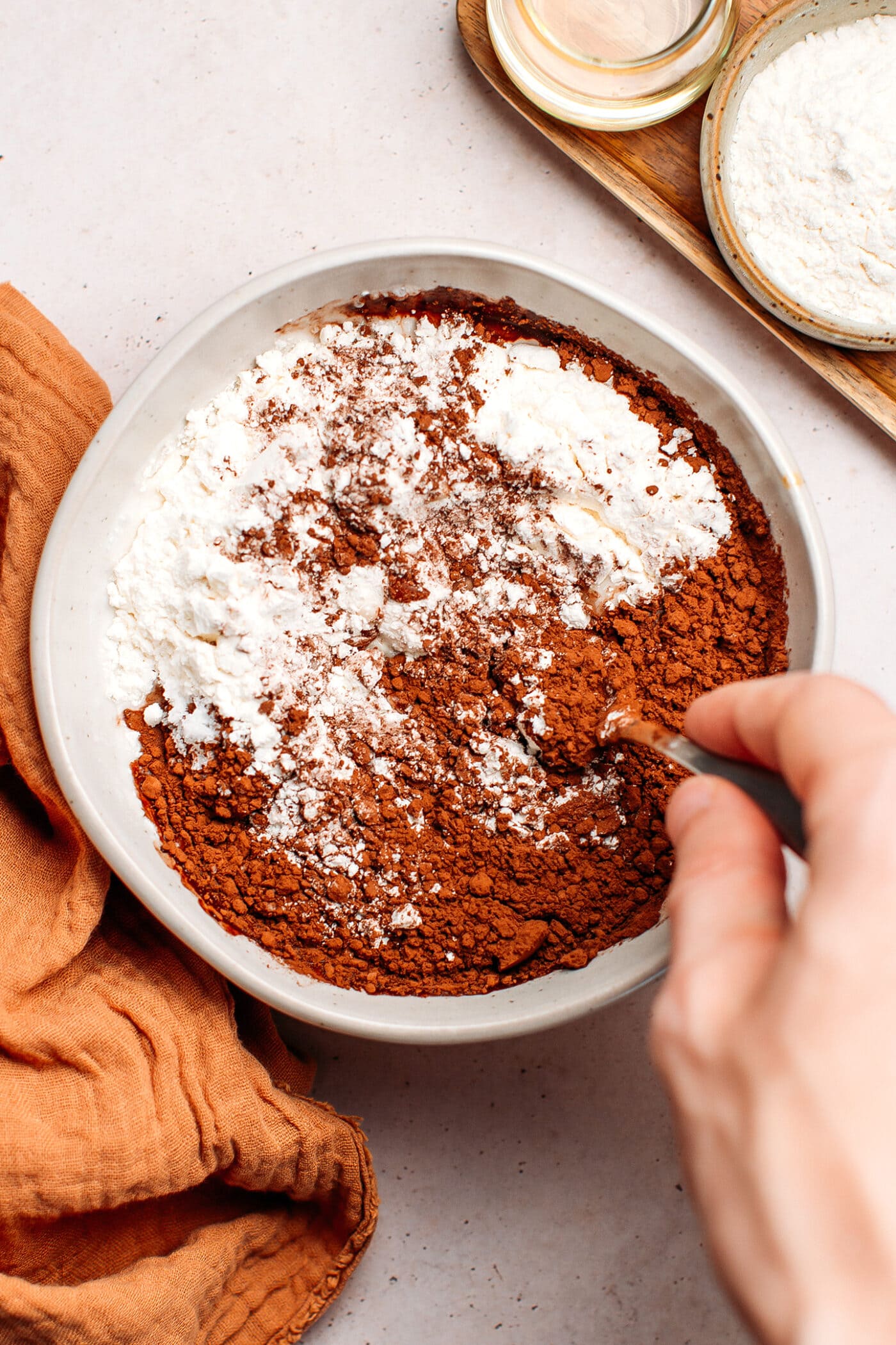 Whisking cacao powder, flour, and almond milk in a small bowl.
