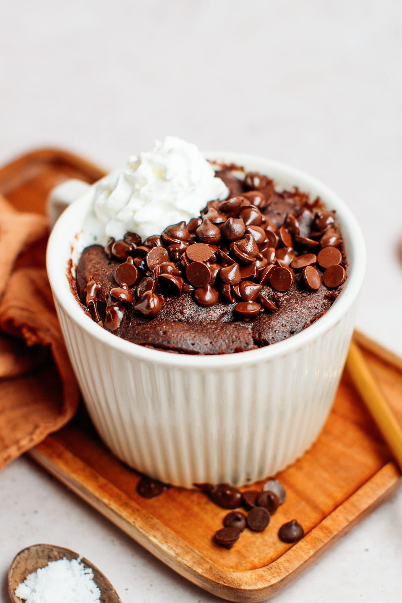 Chocolate mug cake topped with chocolate chips and coconut cream.