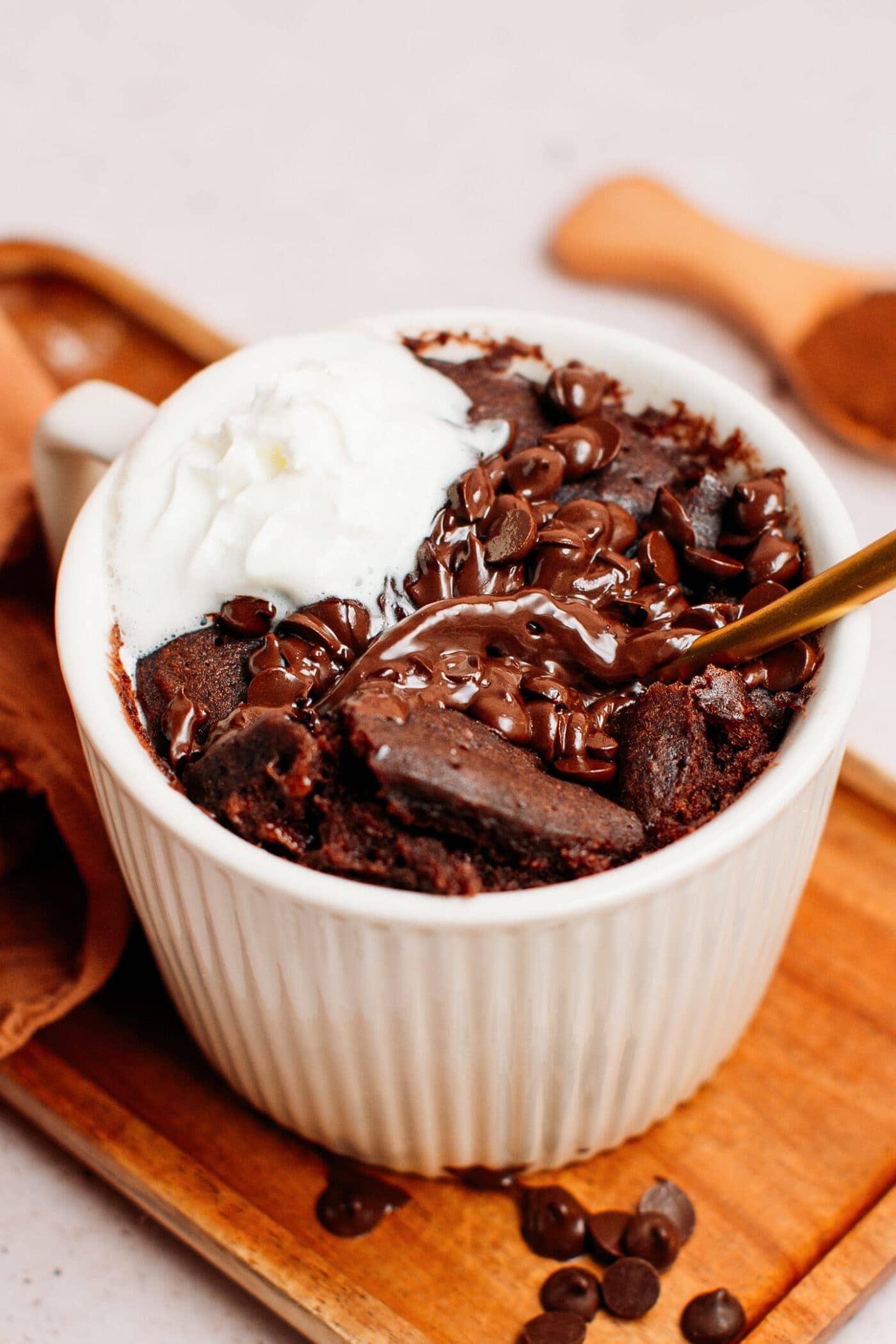 Chocolate mug cake topped with chocolate chips and coconut cream.