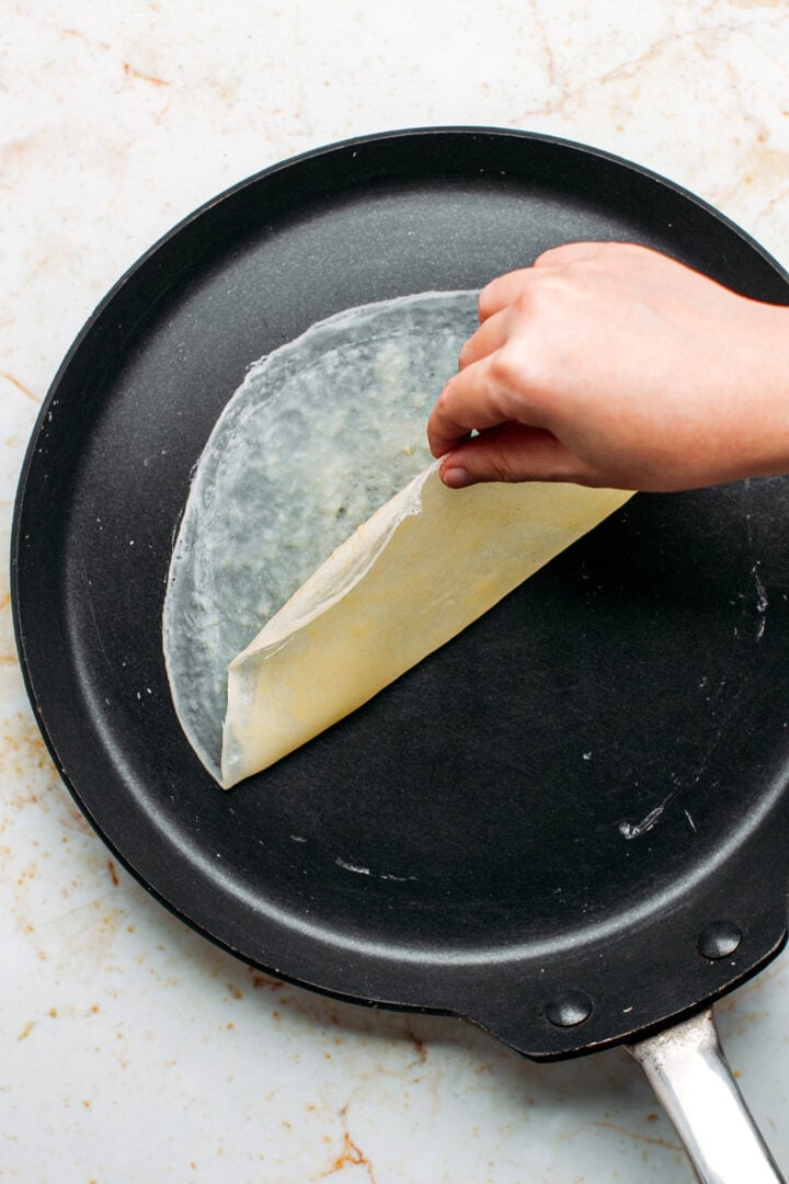 Removing an egg roll wrapper from a pan.