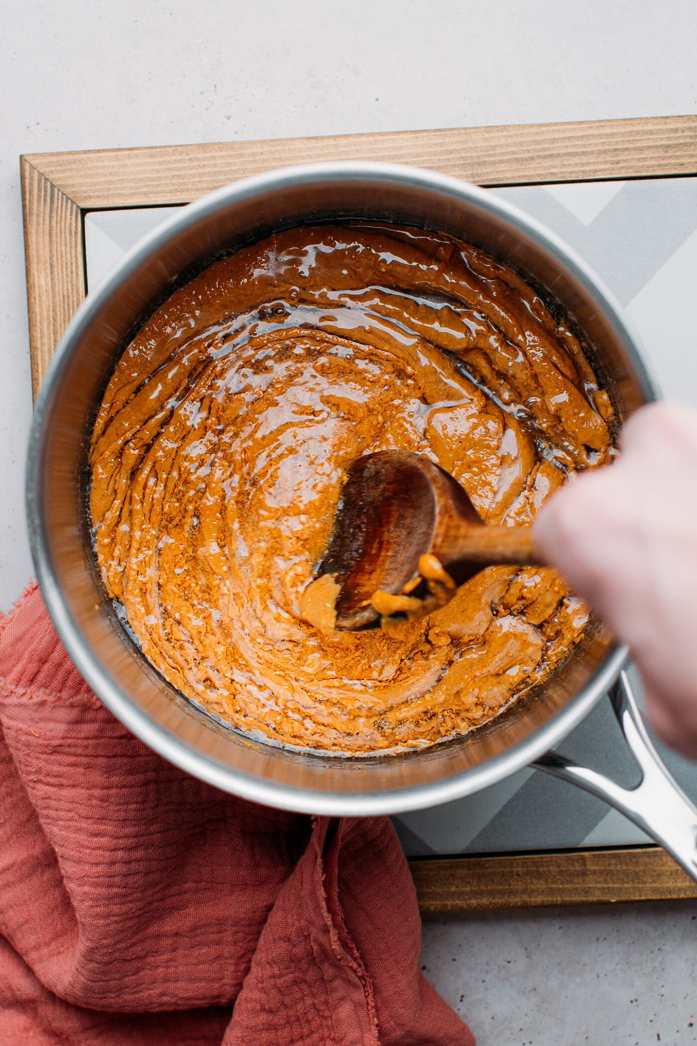 Stirring peanut butter with sugar syrup in a saucepan.