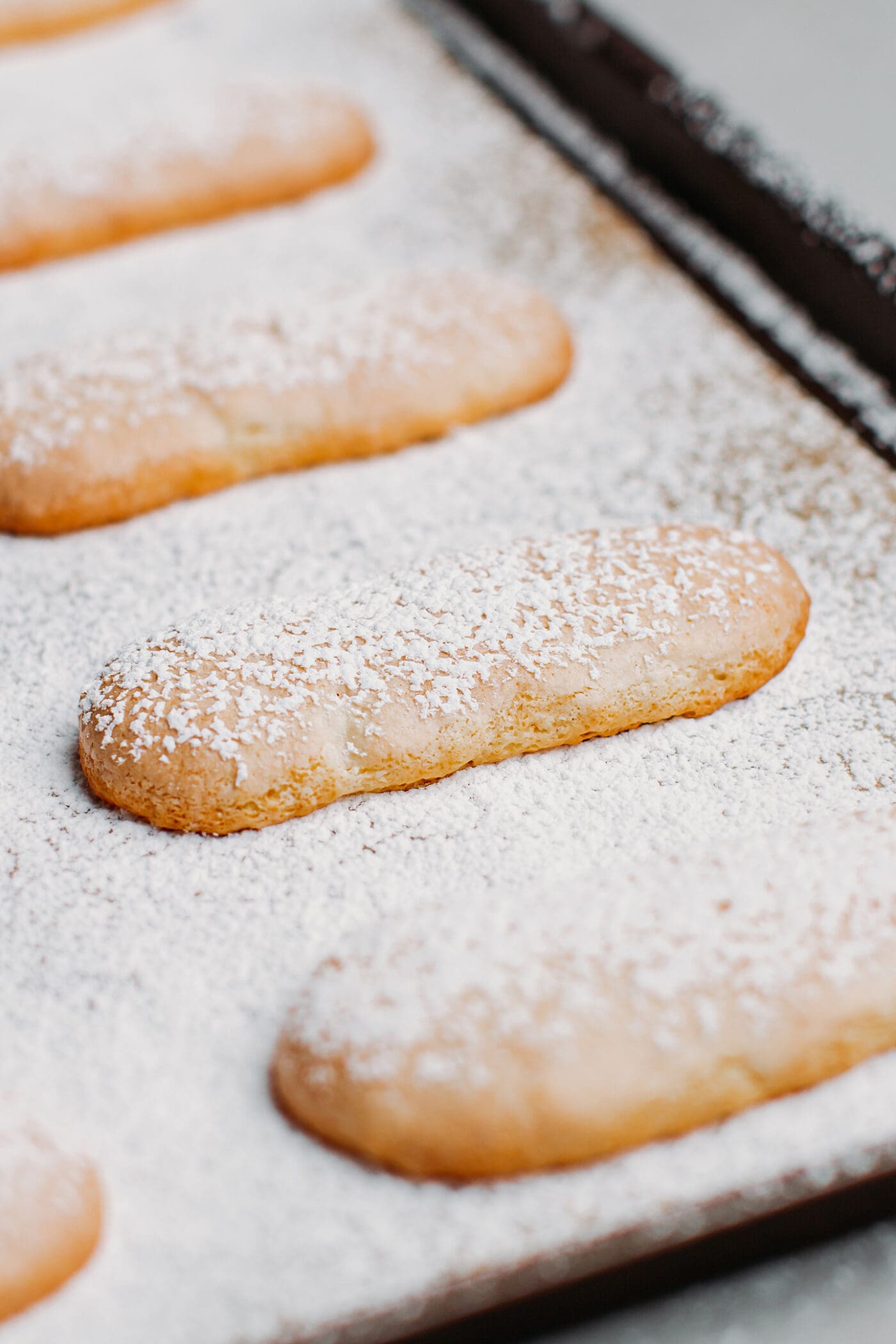 Close-up of vegan ladyfingers on a baking sheet.
