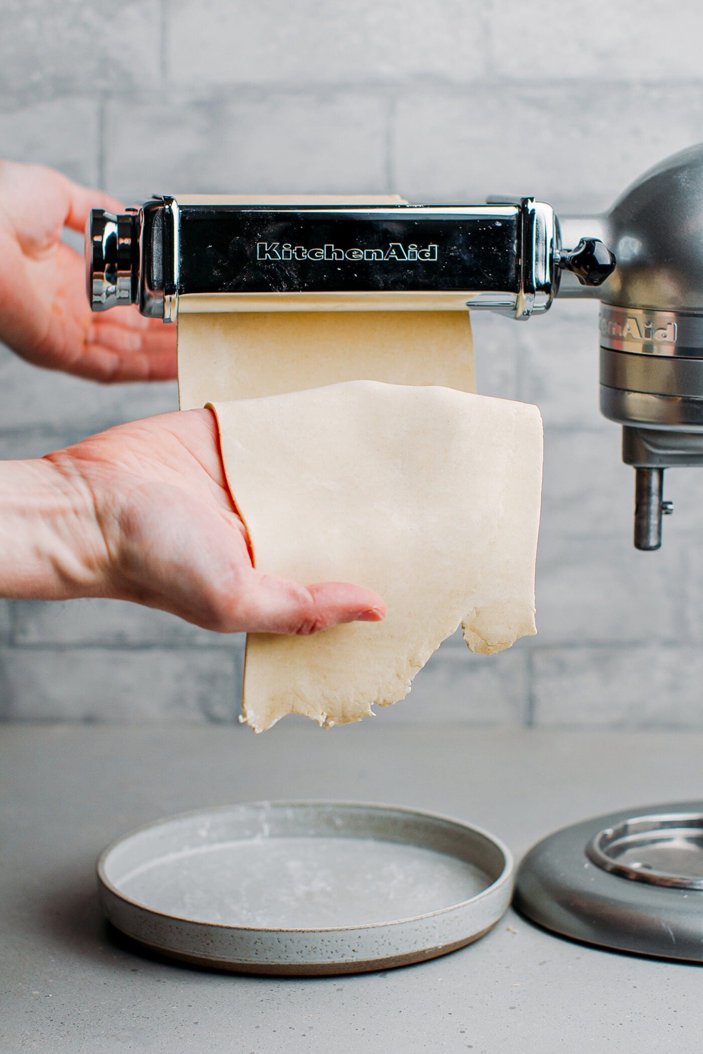 Rolling out pasta dough through a pasta roller.