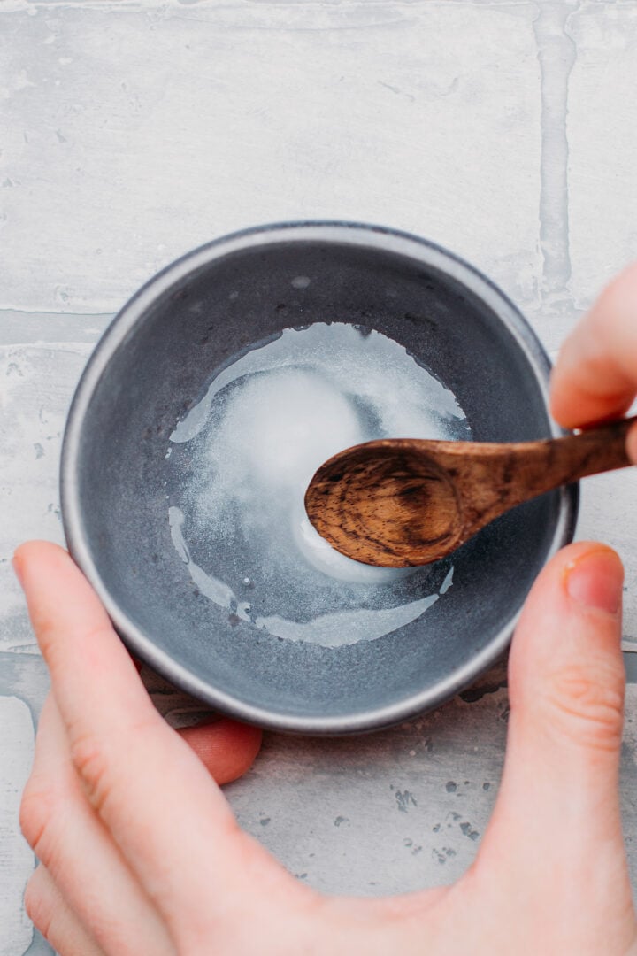 Stirring baked baking soda with water in a small bowl.