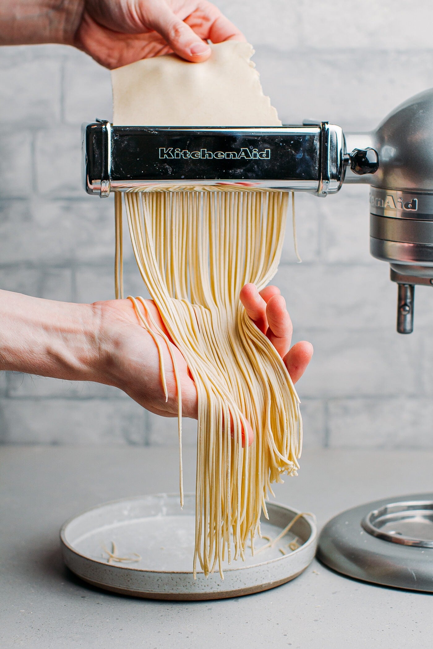 Slicing pasta dough into strips using a pasta cutter.