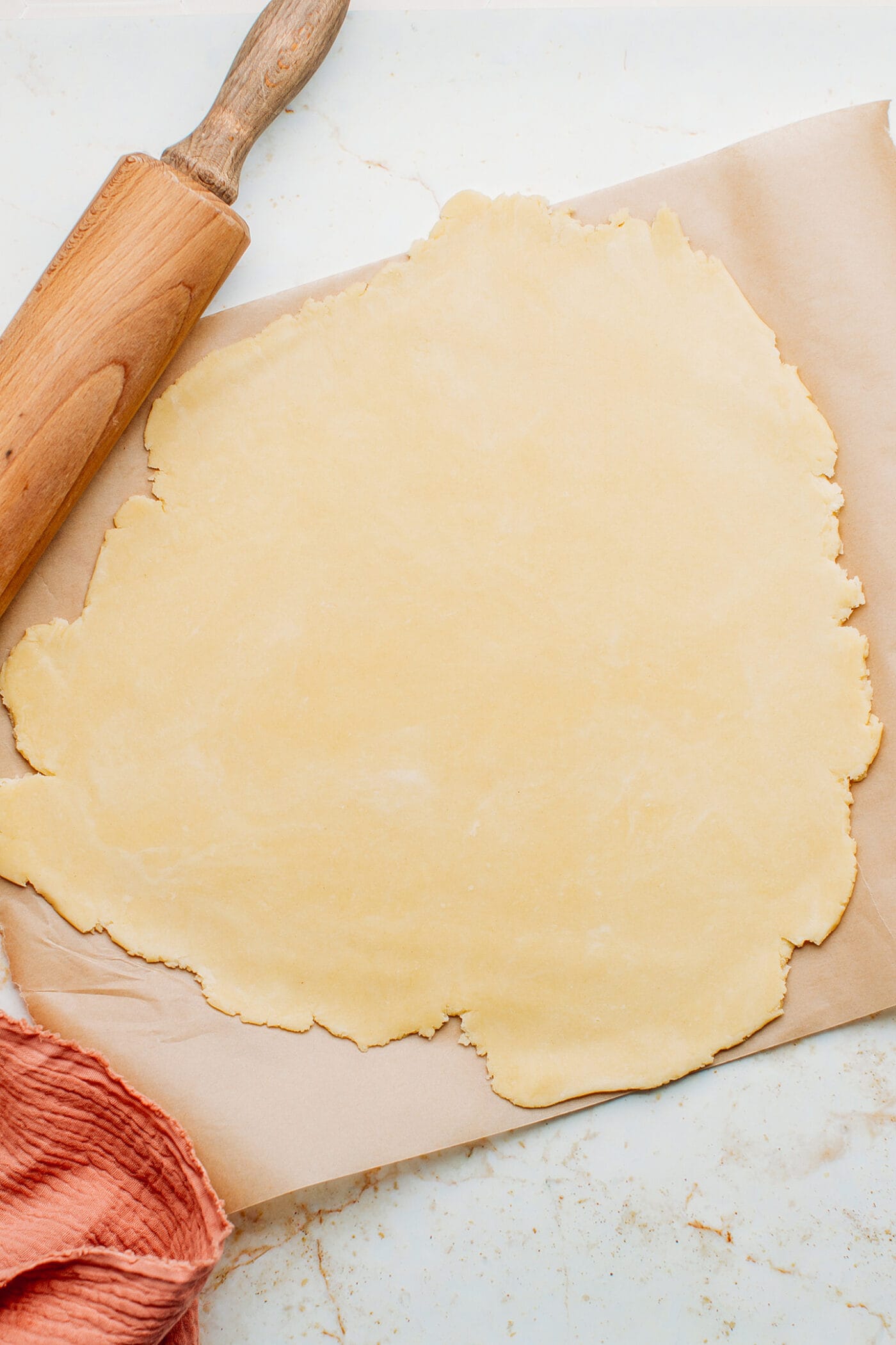 Pie crust flattened on parchment paper.
