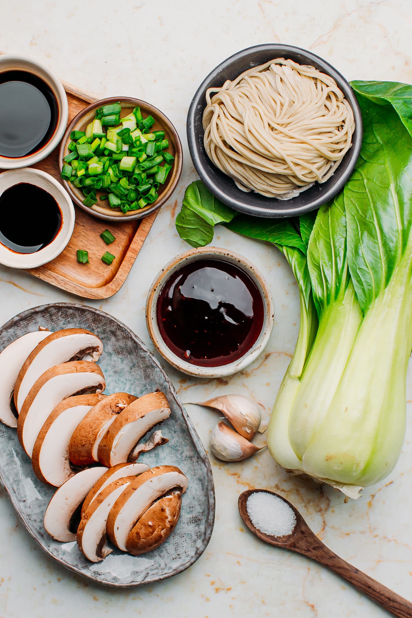 Ingredients like pak choi, garlic, mushrooms, and noodles.