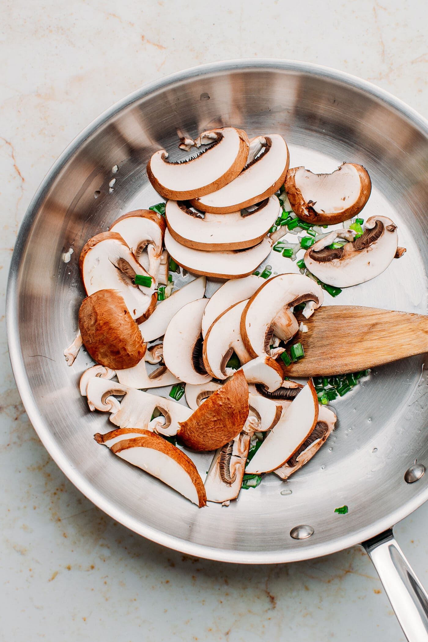 Green onions and mushrooms in a pan.