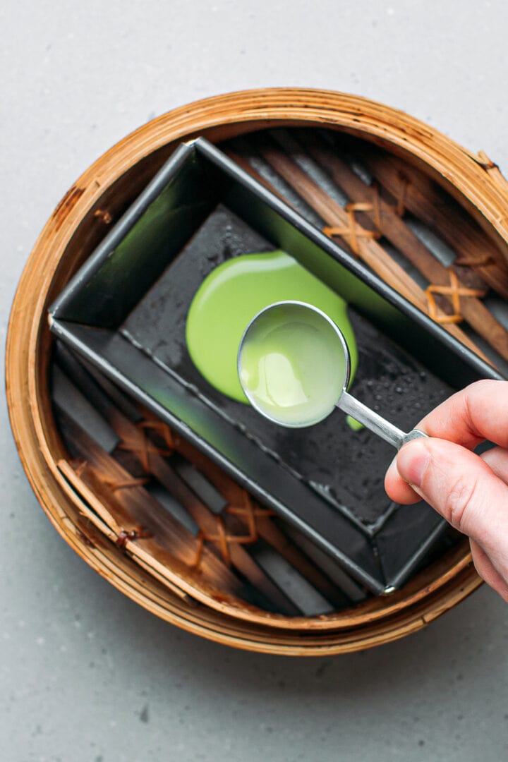 Pouring a pandan-flavored batter into a pan.