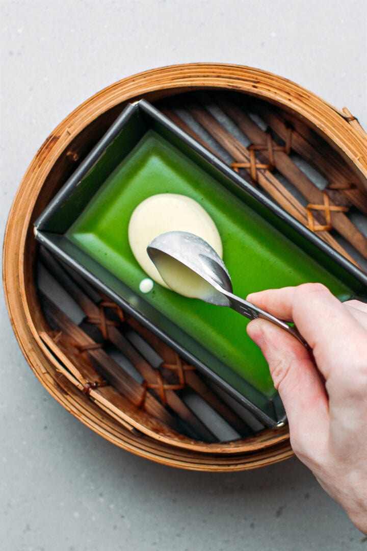 Pouring a mung bean batter into a pan, in a steamer.