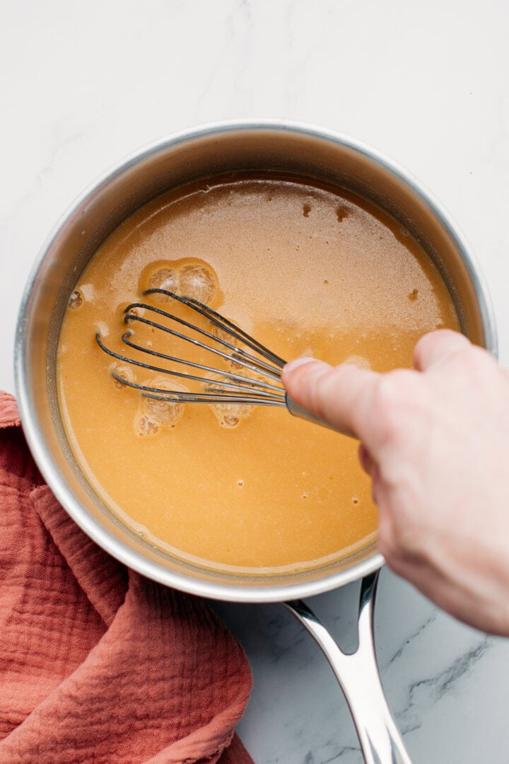 Whisking caramel, almond milk, and agar in a saucepan.