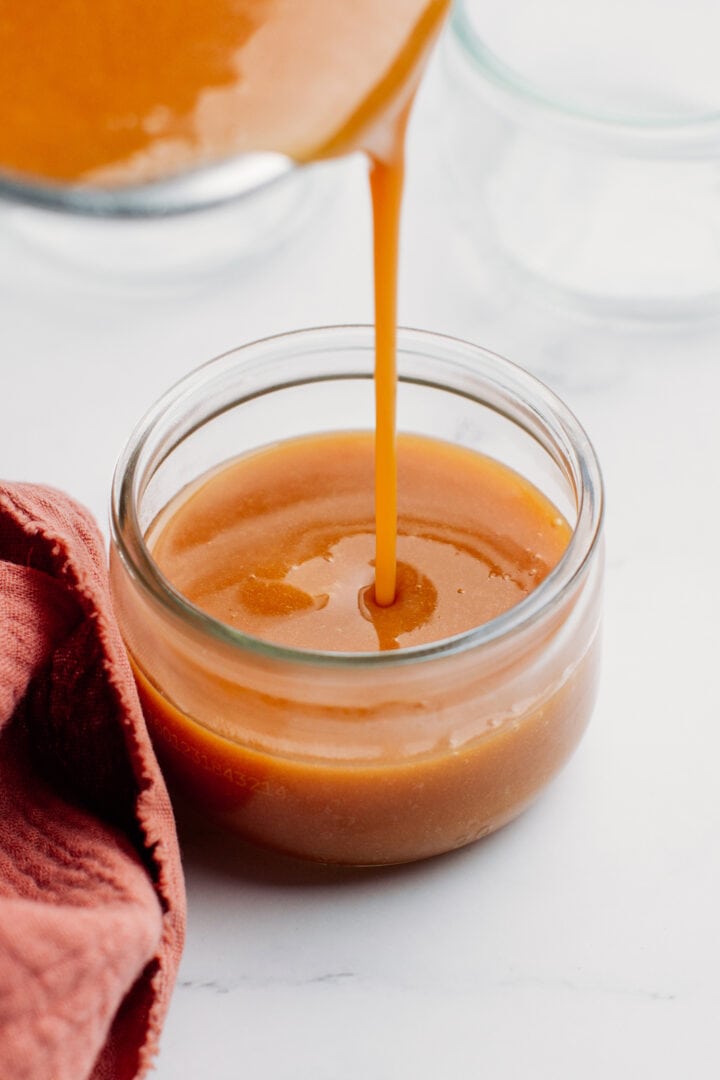 Pouring caramel custard into a glass ramekin.