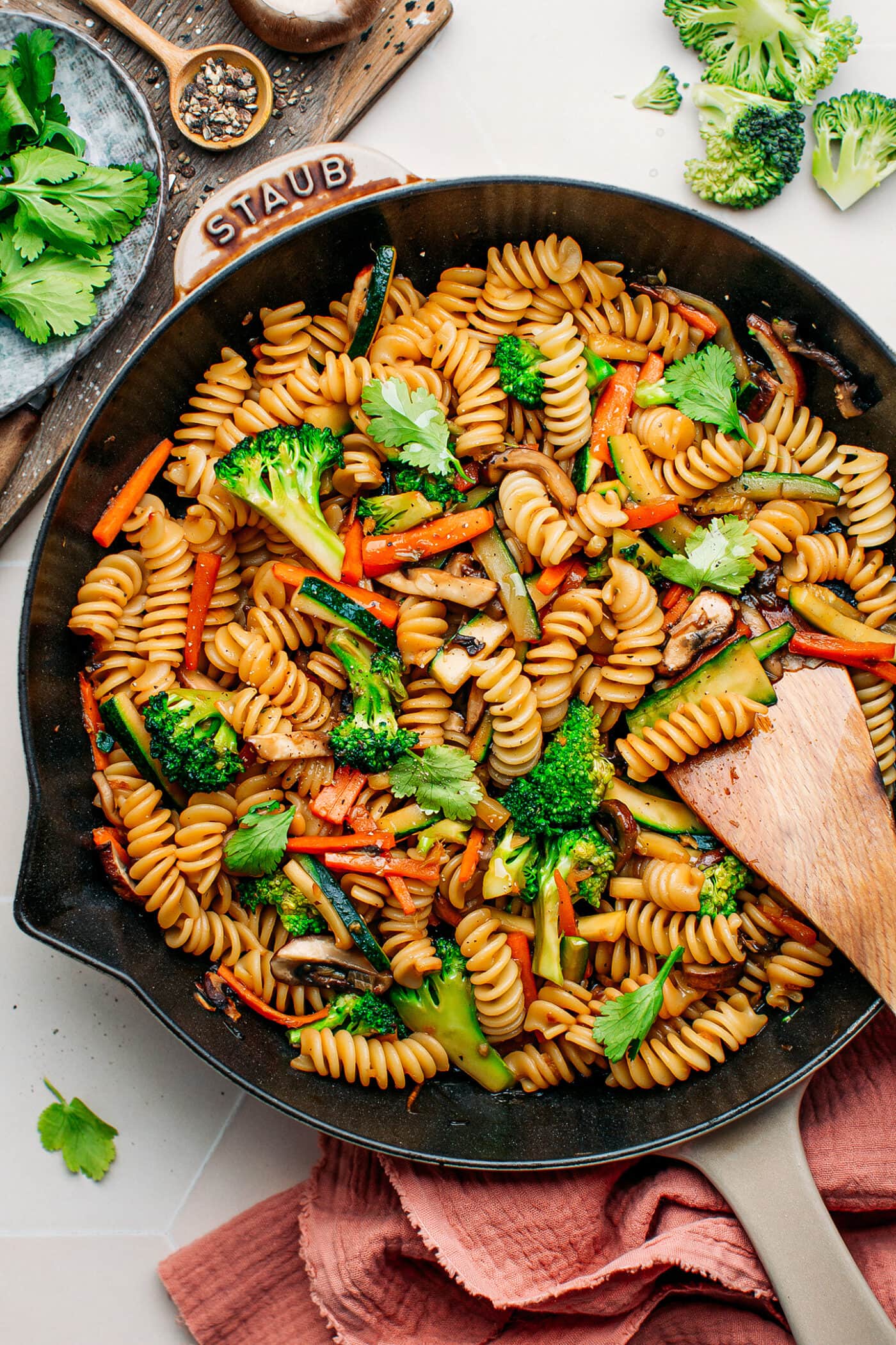 Pasta stir-fry with broccoli, carrots, and mushrooms in a skillet.