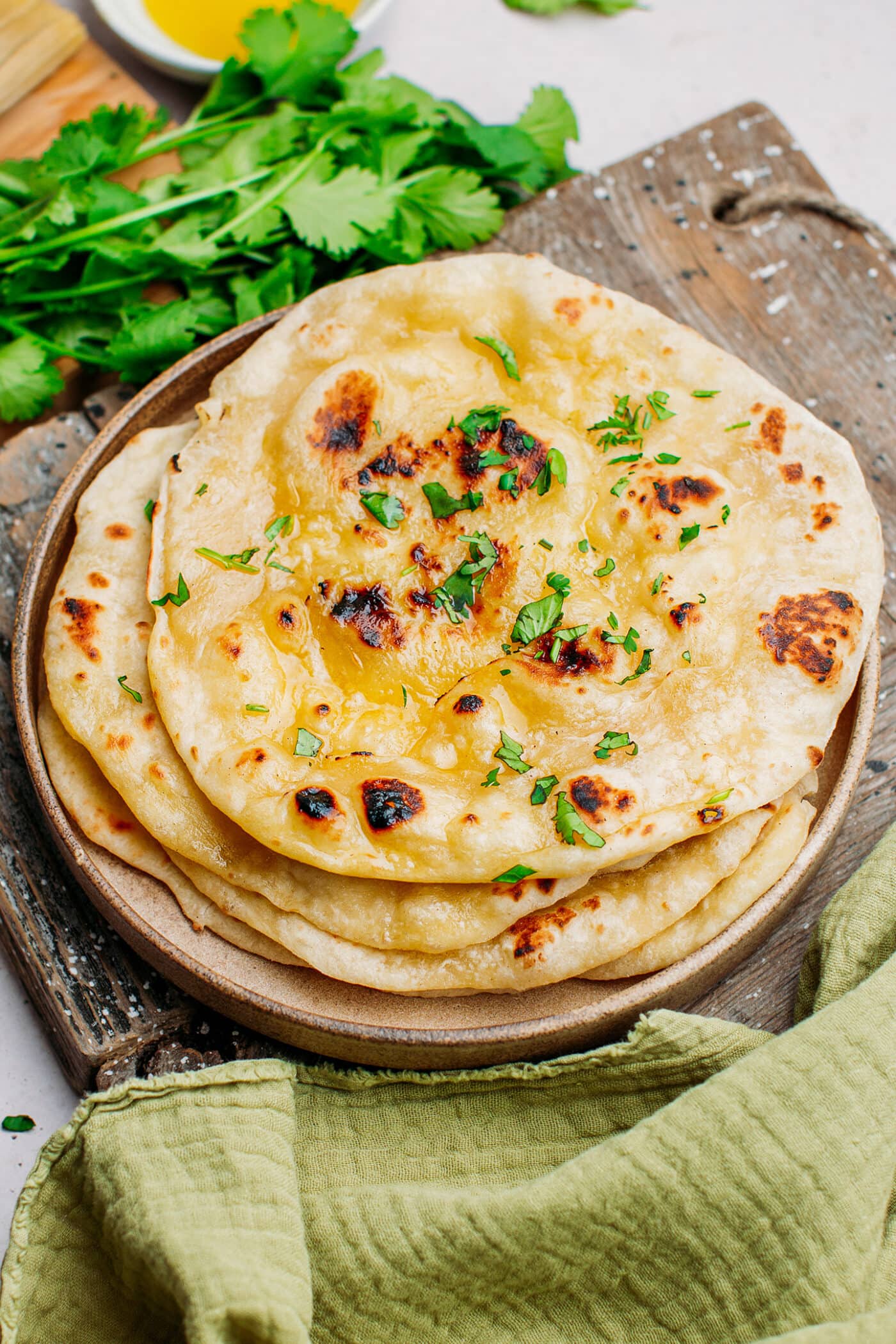 Indian naan on a plate topped with chopped cilantro.