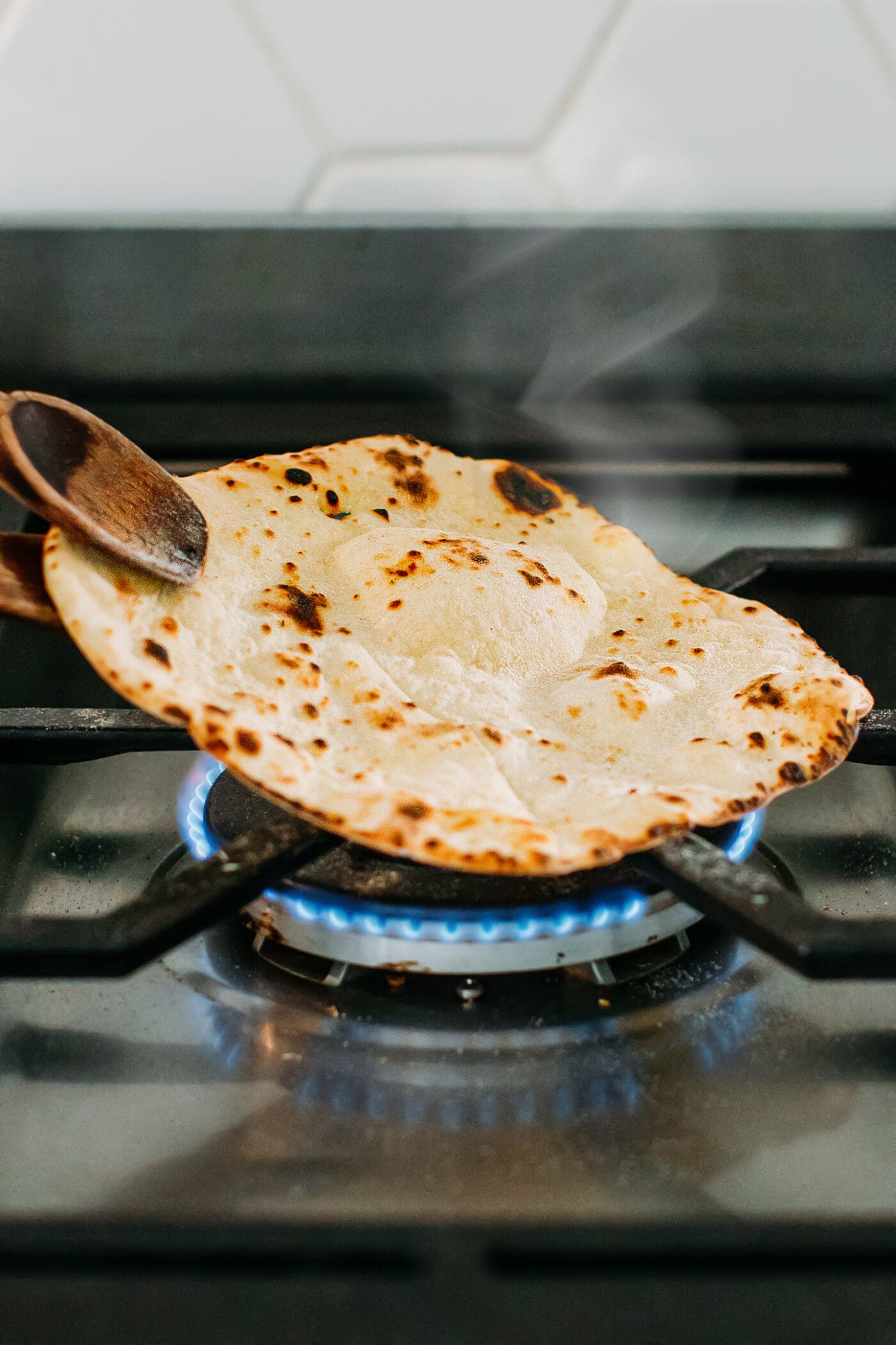 Charring naan on an open flame.