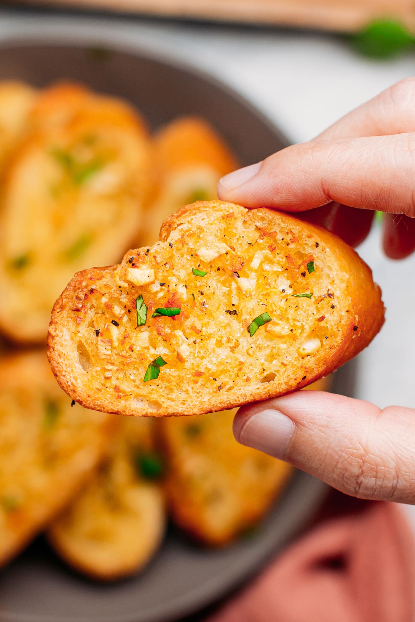 Holding a slice of garlic bread.