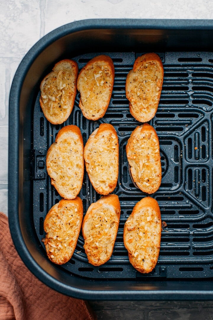 Garlic bread slices in the basket of an air fryer.