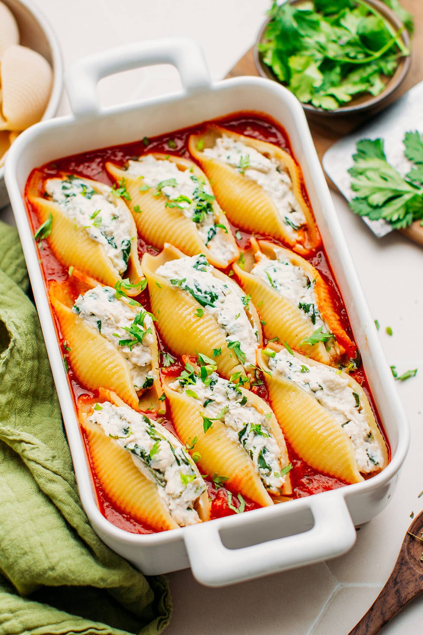 Vegan stuffed shells topped with chopped parsley in a baking dish.