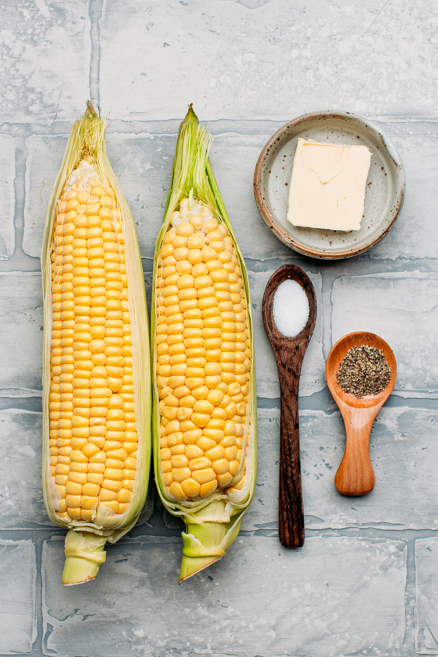 Ingredients like corn on the cob, butter, salt, and pepper.
