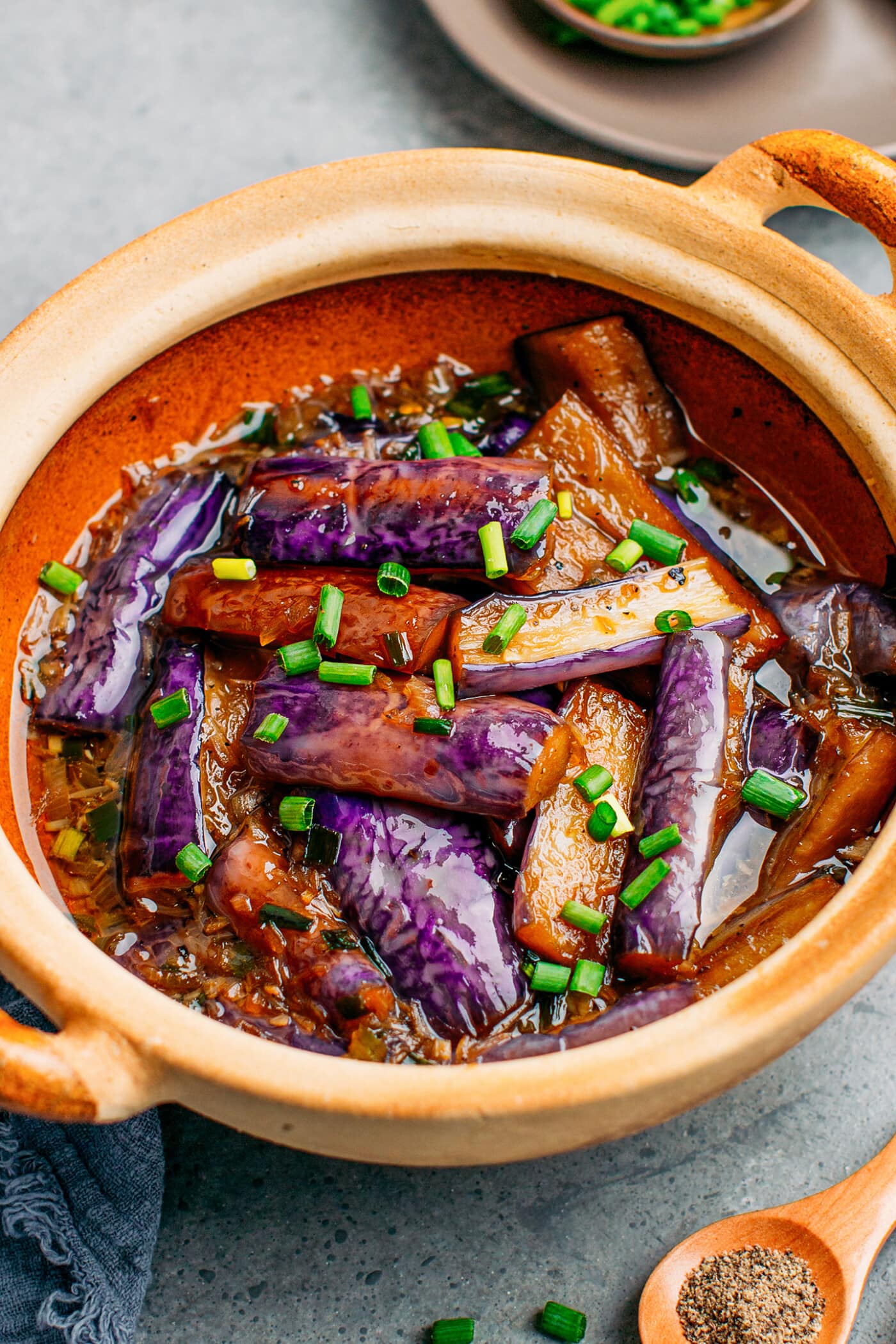 Chinese eggplants in a clay pot with green onions.