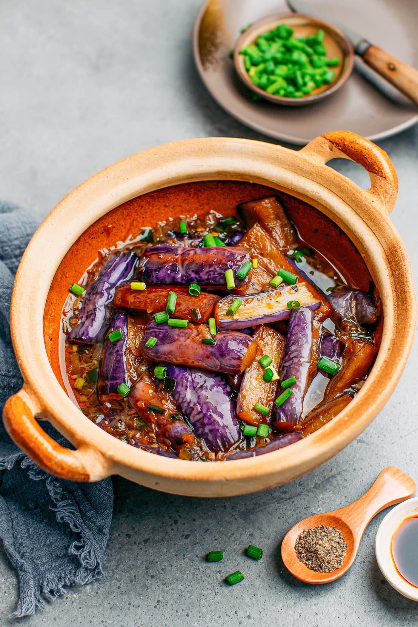 Chinese eggplants with green onions in a clay pot.