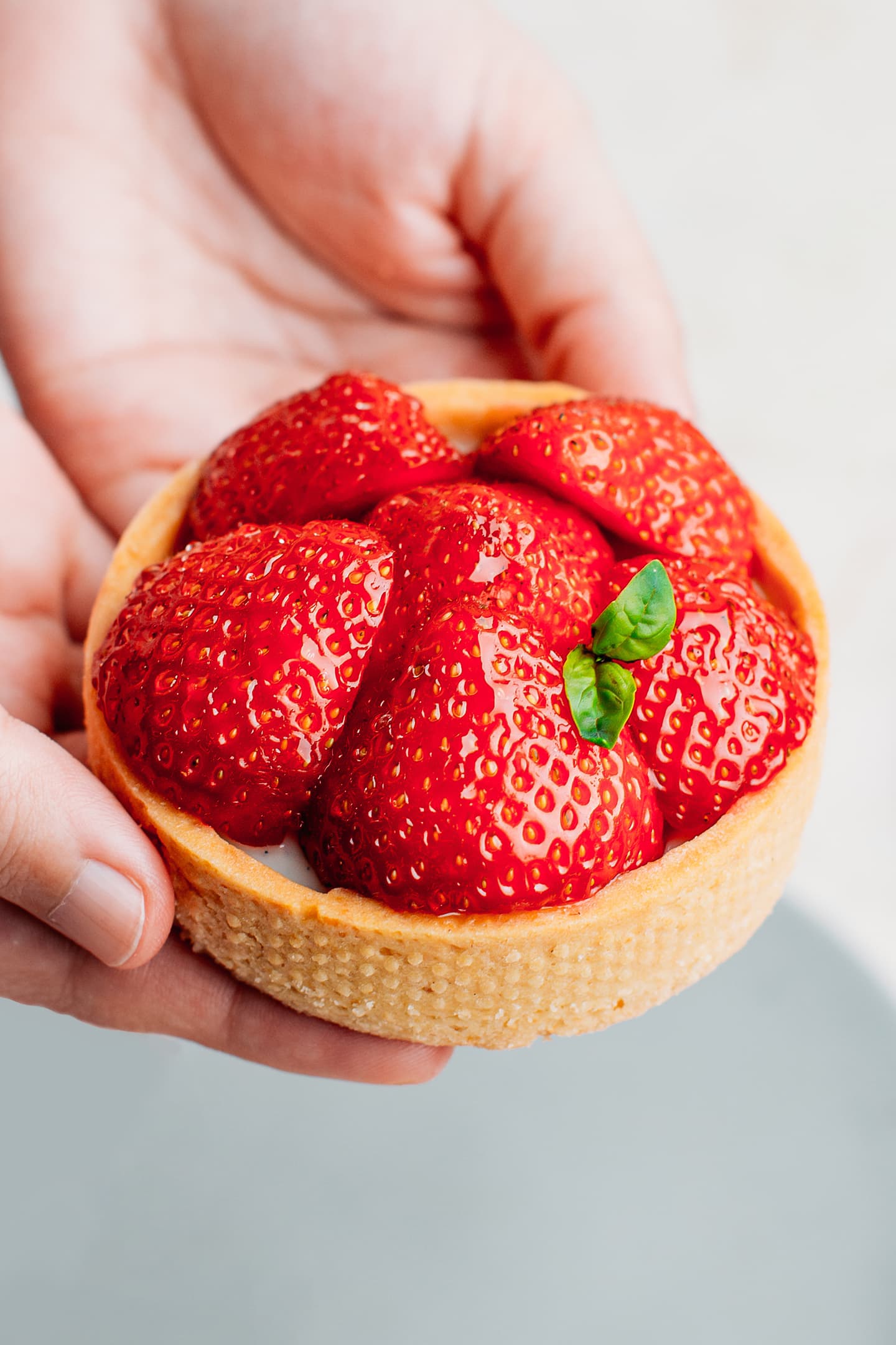 Holding a strawberry tartlet.