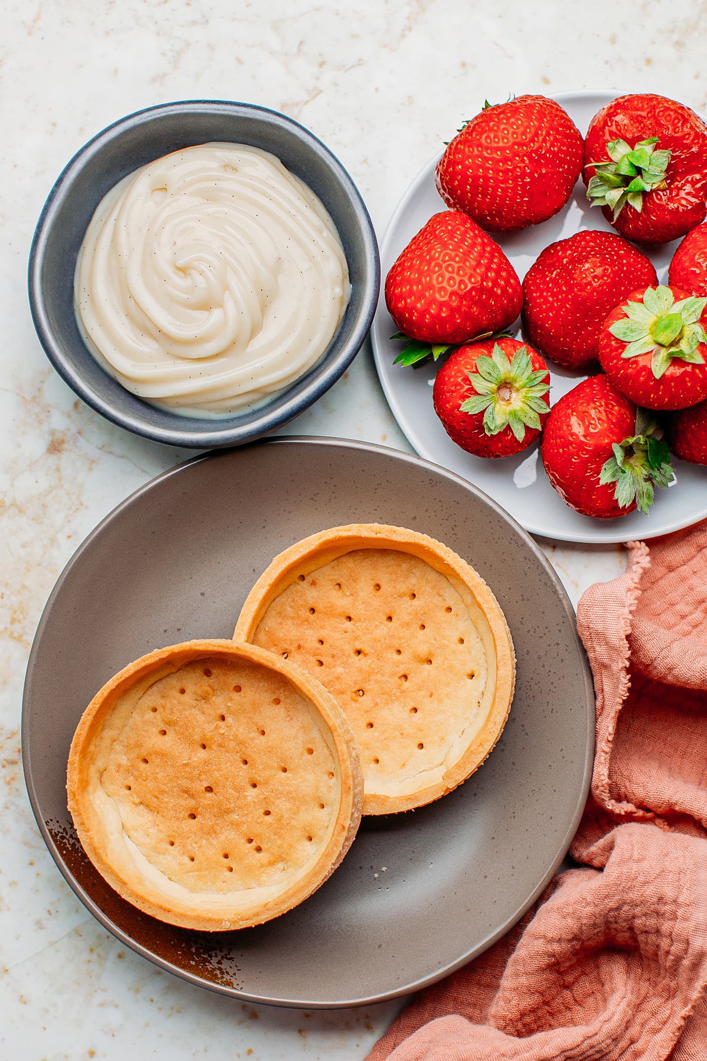 Ingredients like tartlet shells, fresh strawberries, and pastry cream.