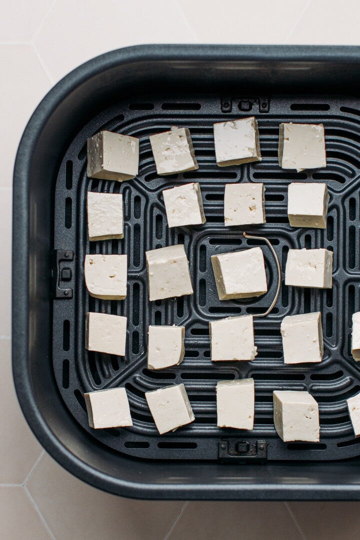 Tofu in the basket of an air fryer.