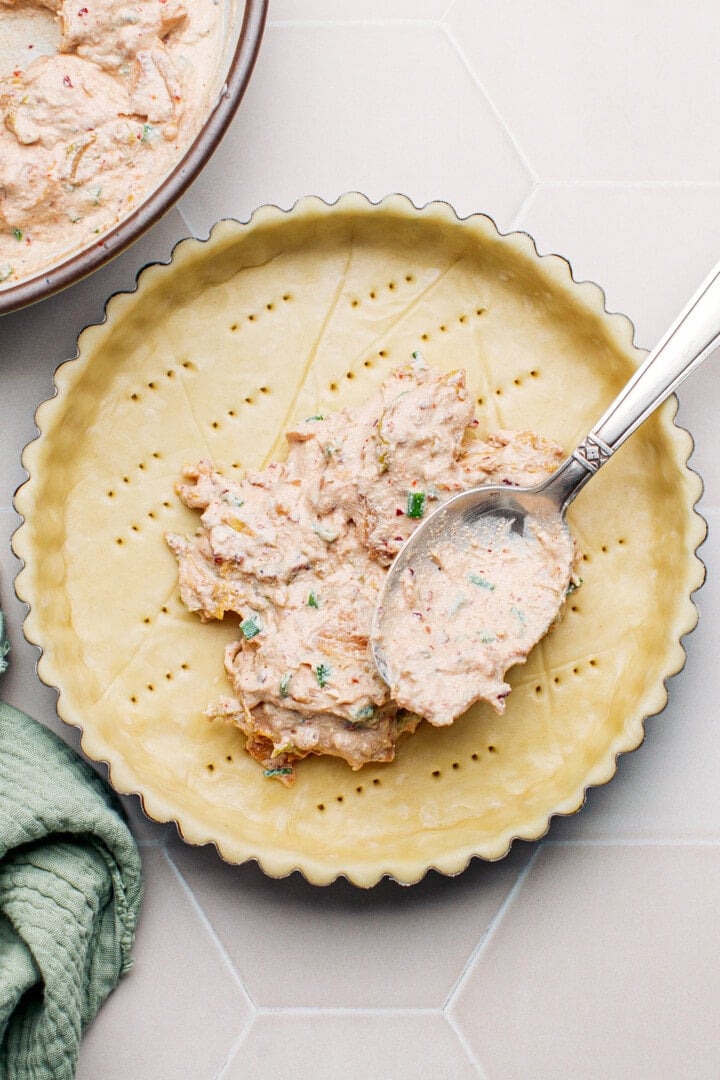 Spreading kimchi filling on top of an unbaked pie crust.
