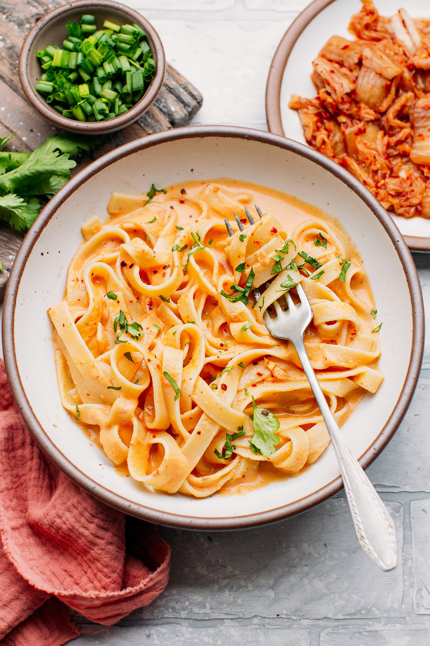 Fettuccine coated with kimchi sauce and topped with chopped cilantro.