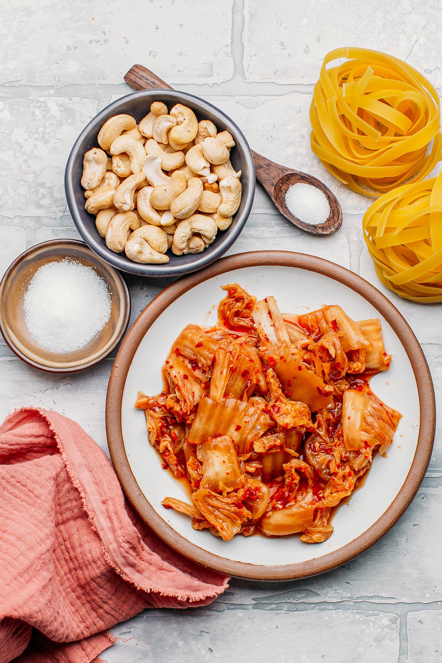 Ingredients like kimchi, raw cashews, sugar, and pasta.
